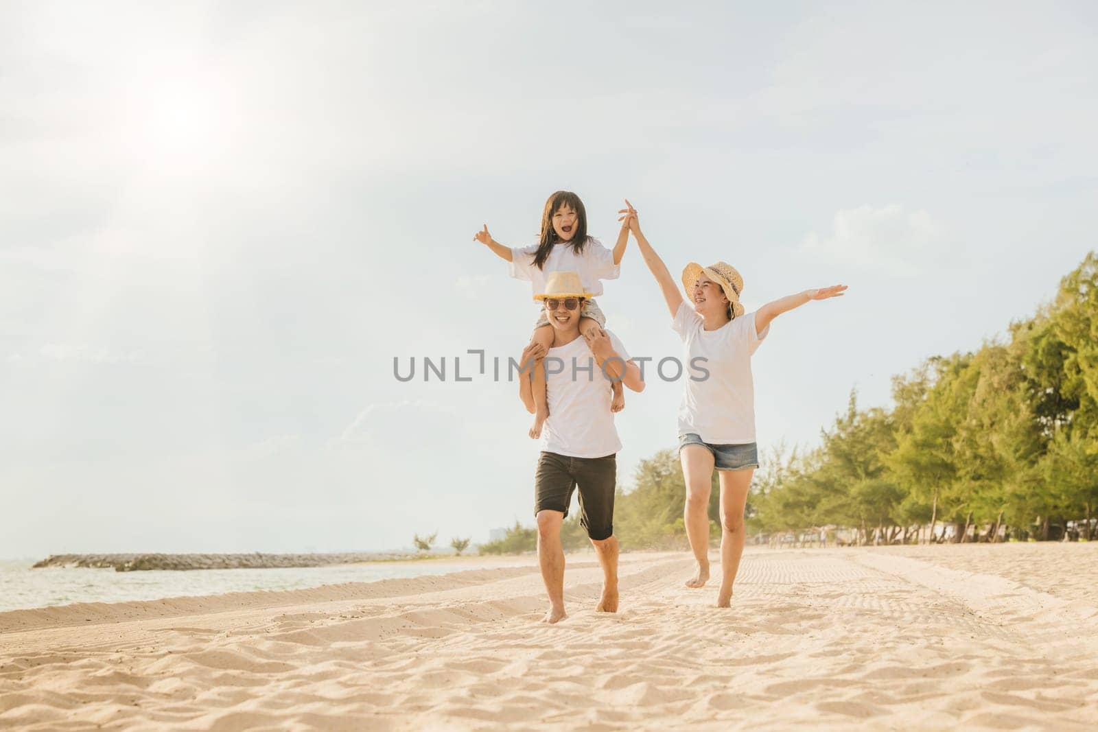 Family day. Happy family people having fun in summer vacation run on beach, daughter riding on father back and mother running at sand beach, family trip playing together outdoor, traveling in holiday