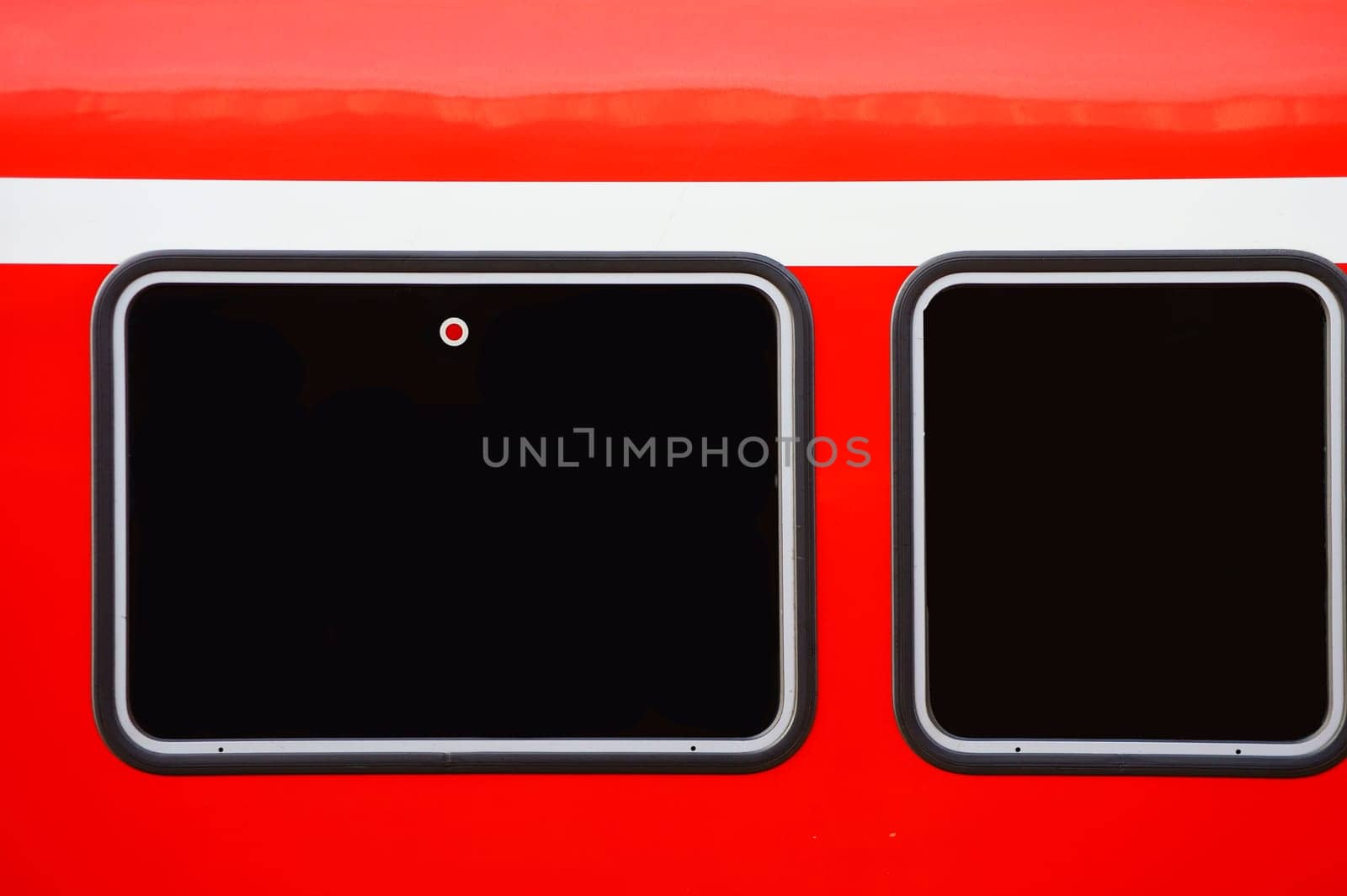 The close-up of the outer body of a passenger train with two windows.