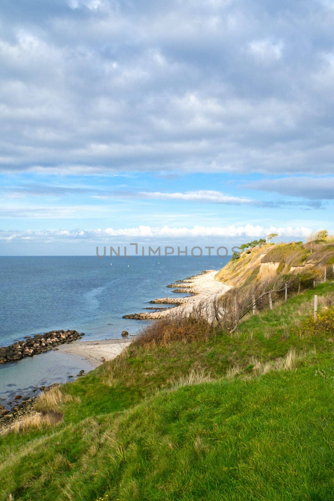 Hundested, Denmark on the cliff overlooking the sea. Baltic Sea coast, grassy meadow, beach. Clouds on horizon. Landscape photo from Scandinavia.