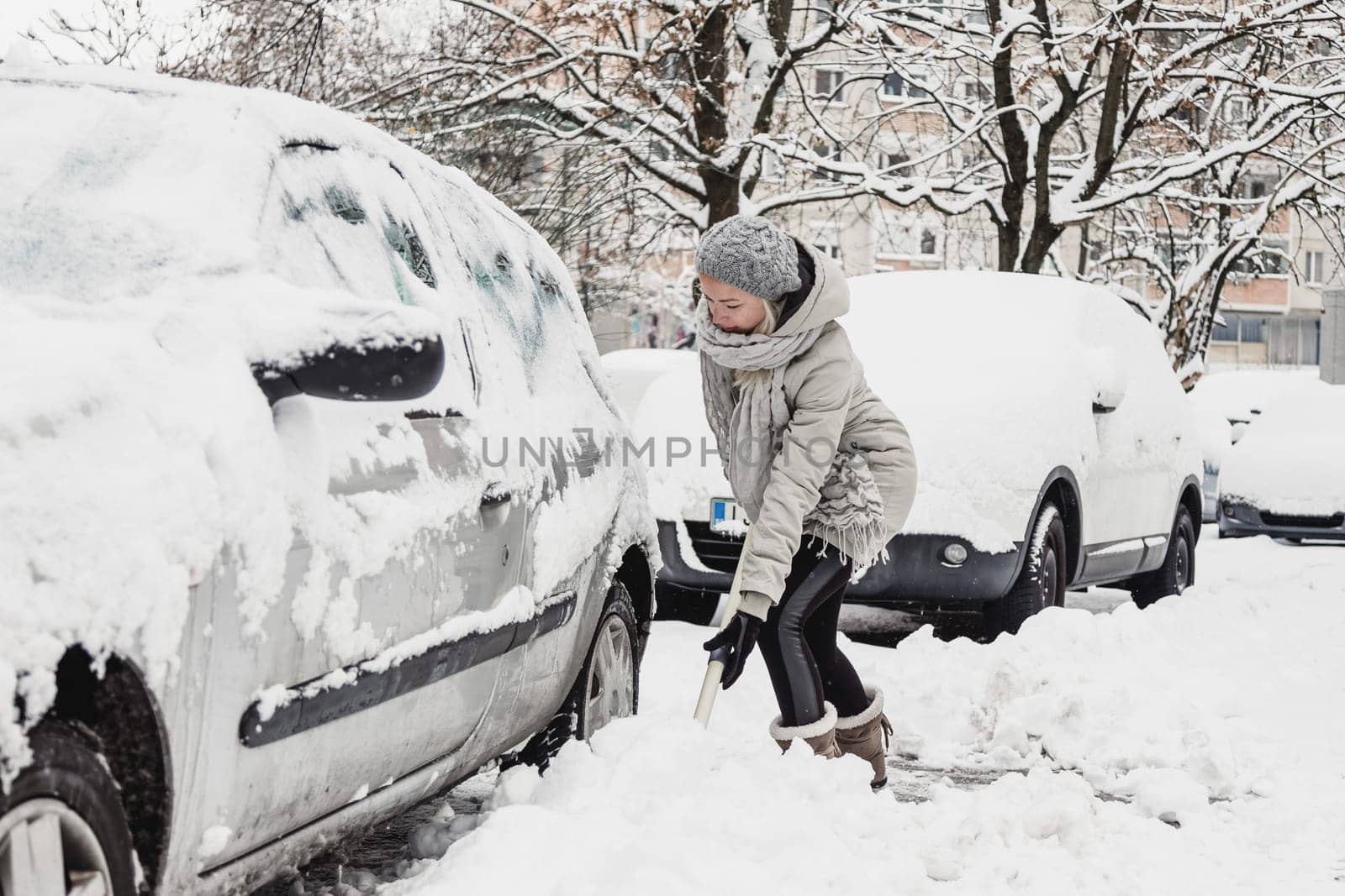 Independent woman shoveling her parking lot after a winter snowstorm.