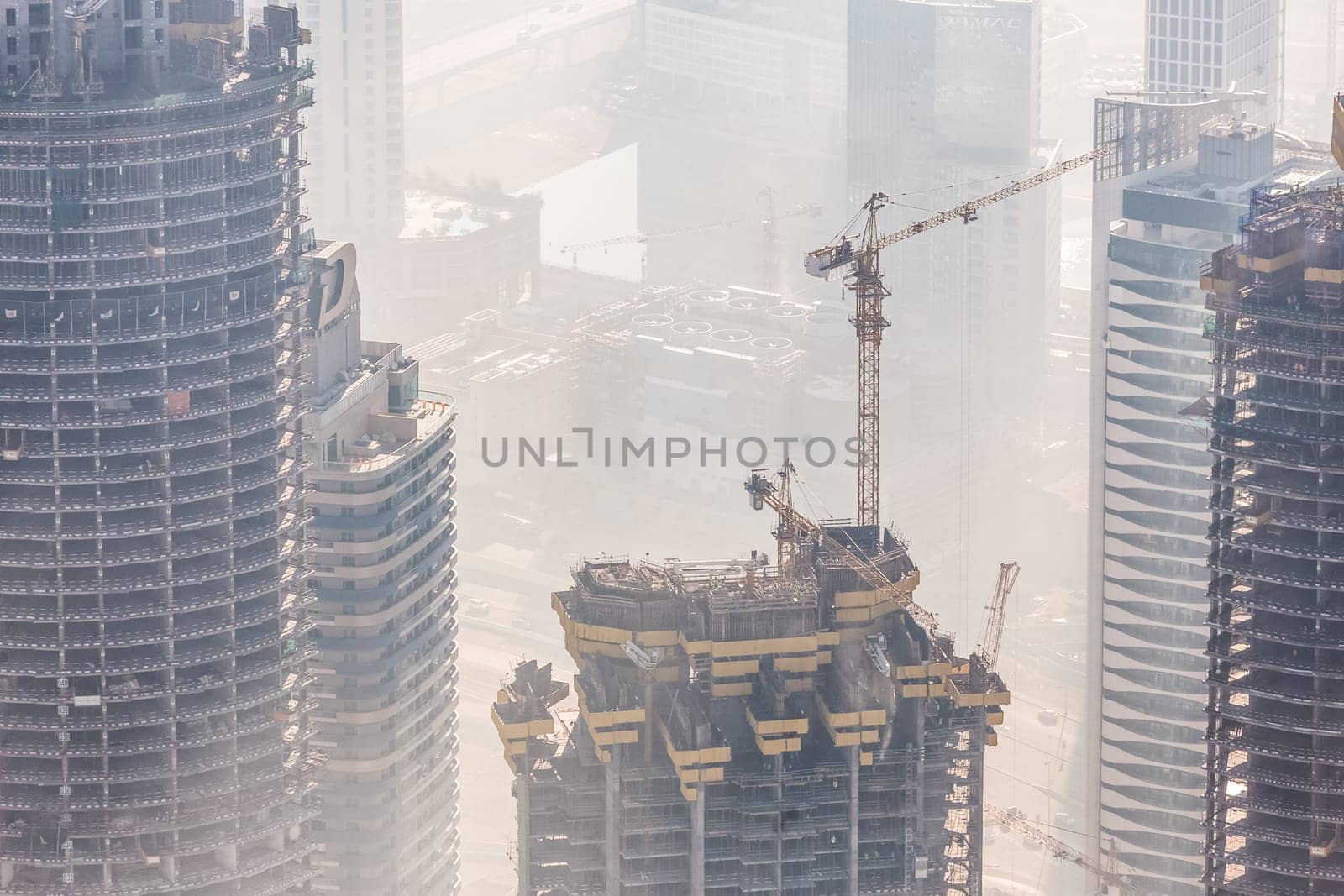 Huge skyscrappers construction site with cranes on top of buildings. Rapid urban and construction sector development or inflation of real estate bubble.
