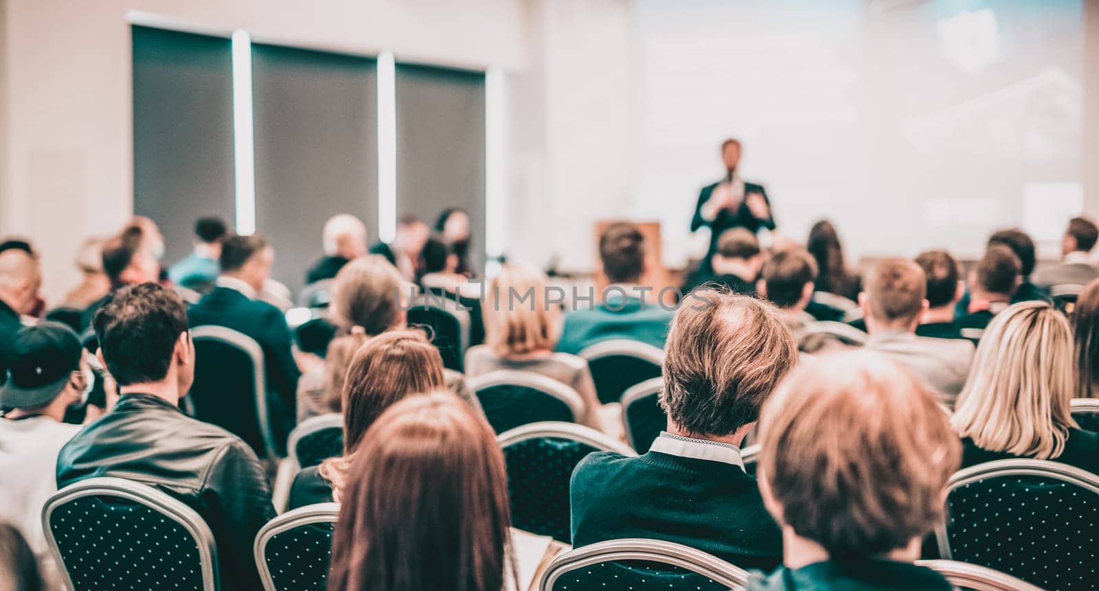 Speaker giving a talk in conference hall at business event. Rear view of unrecognizable people in audience at the conference hall. Business and entrepreneurship concept