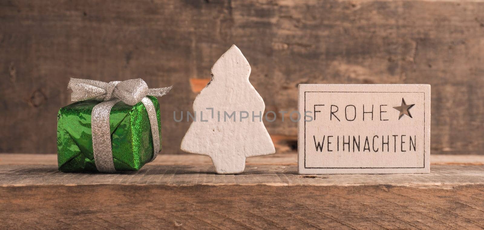 Frohe Weihnachten on a small sign, German Merry Christmas with decoration on a wooden background