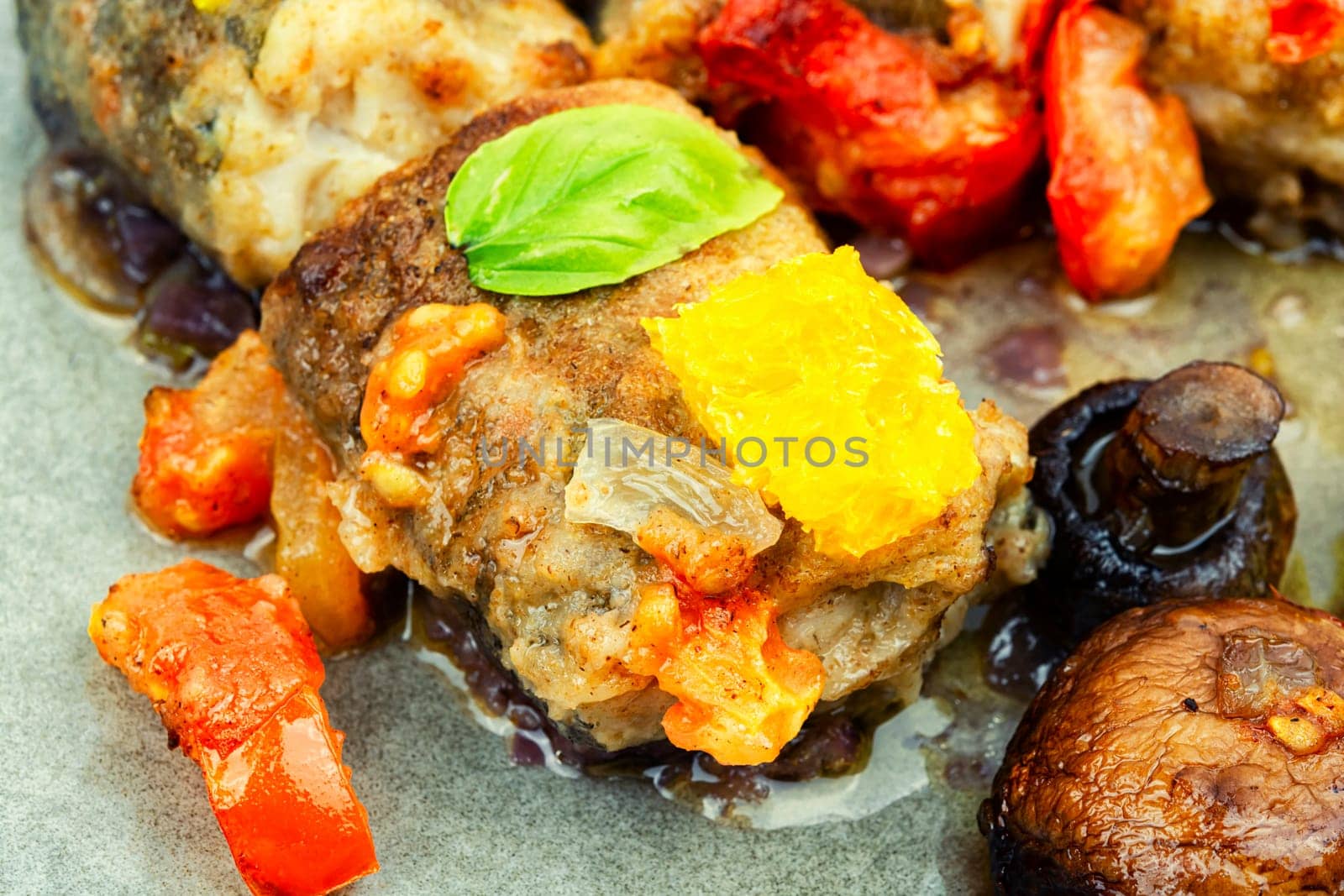 Fried hake fish grilled with orange, tomato and mushrooms. Close up