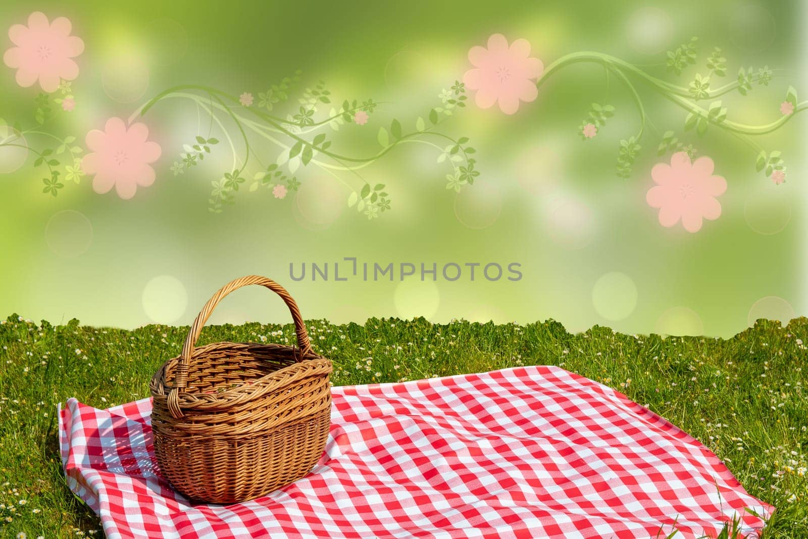 Red checked picnic blanket with empty basket on a meadow over abstract spring background. Beautiful backdrop for your product placement or montage.