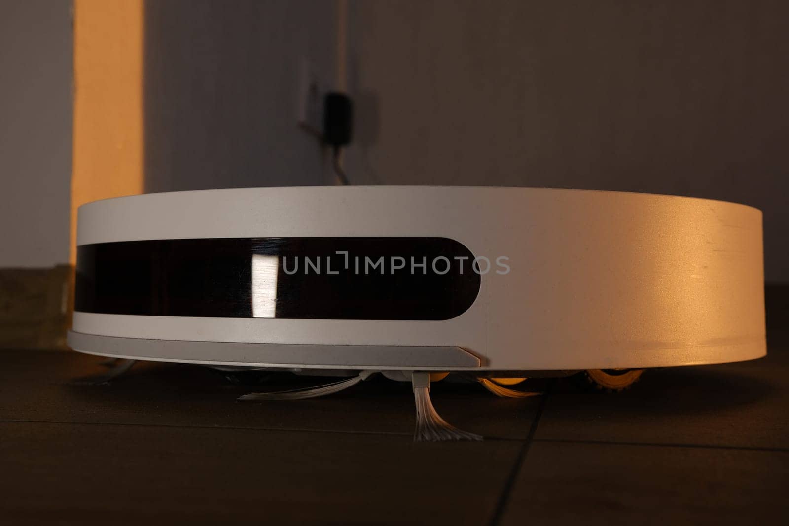 white vacuum robot cleaner close up with sunset light on the brown dalle with beautiful flares and dust around.