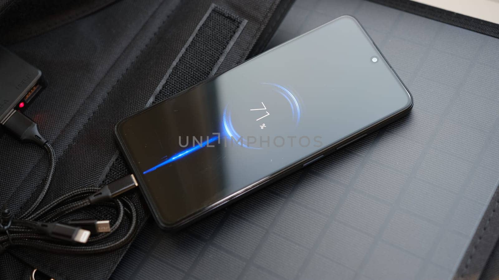 Hands plug in portable solar panel charging smartphone by mutlipurpose cable, power bank, watches, laptops. Clean energy for using in camping or at home when NO electricity