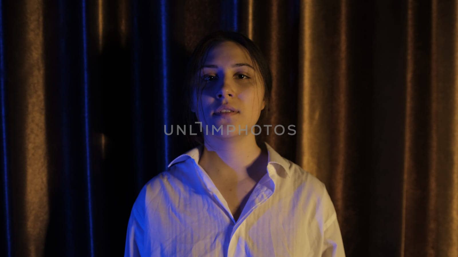 Nervous woman in white shirt in blue and yellow light breathing deeply with focus breathing, calming down after quarrel, Concept of abuse in relationships. Mental and physical violance woman.