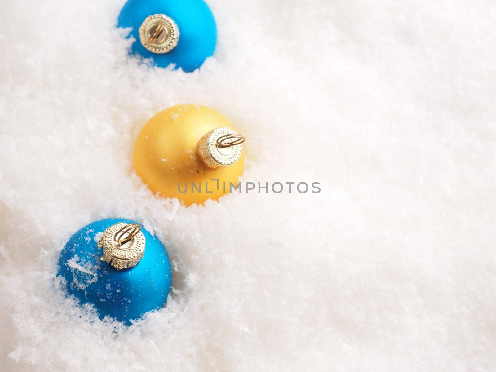 Blue and golden vintage Christmas baubles in the snow with space for text, seasonal backdrop