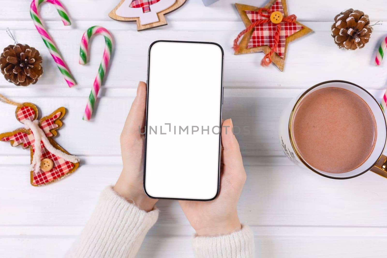 Close up woman holding phone with empty white screen mockup over decorated festive background, celebrating Christmas, customer shopping online, purchasing gifts, browsing gadget apps