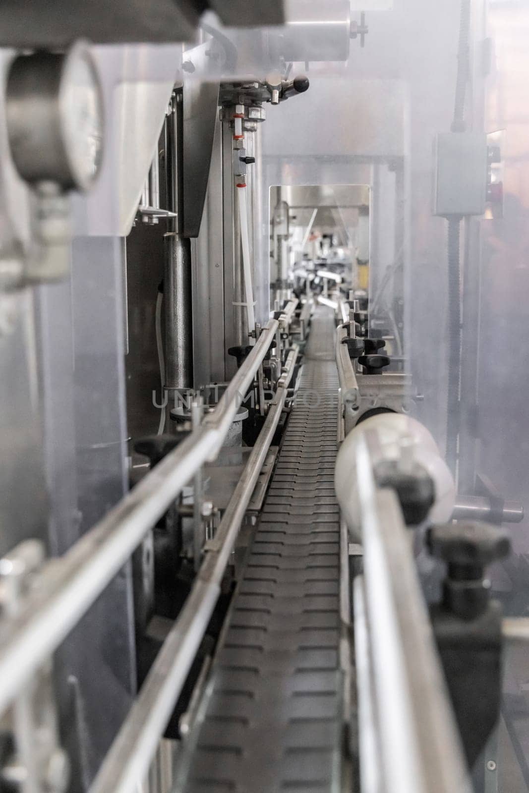 Industrial bottling machine at modern wine factory in Italy, close up. Automatic conveyor line for wine-producing