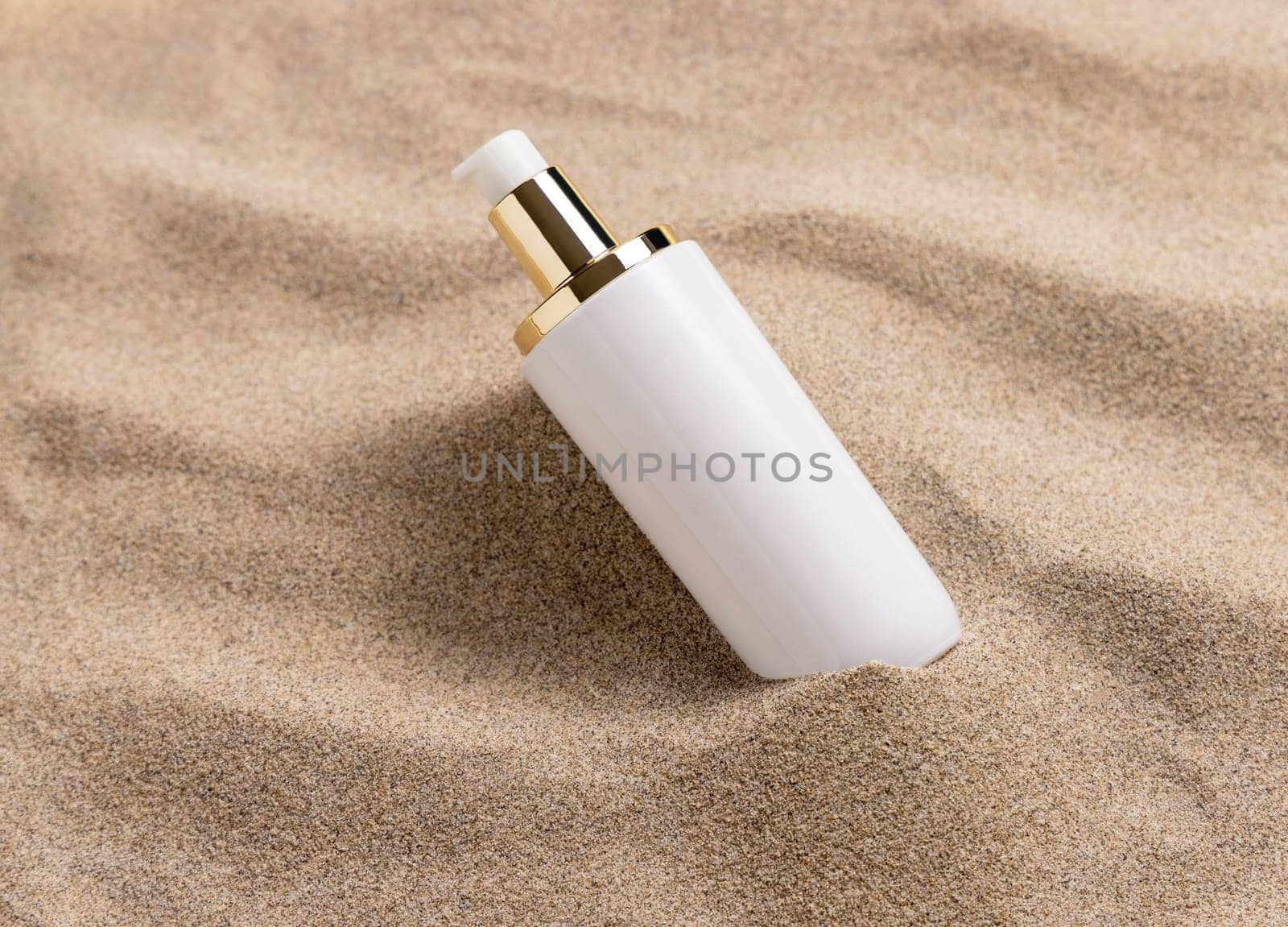 Blank one pump Cream bottle with blank label on beige sand close up. Cosmetic packaging mockup. Natural skincare product for beauty routine. Summer tropical vacation mood