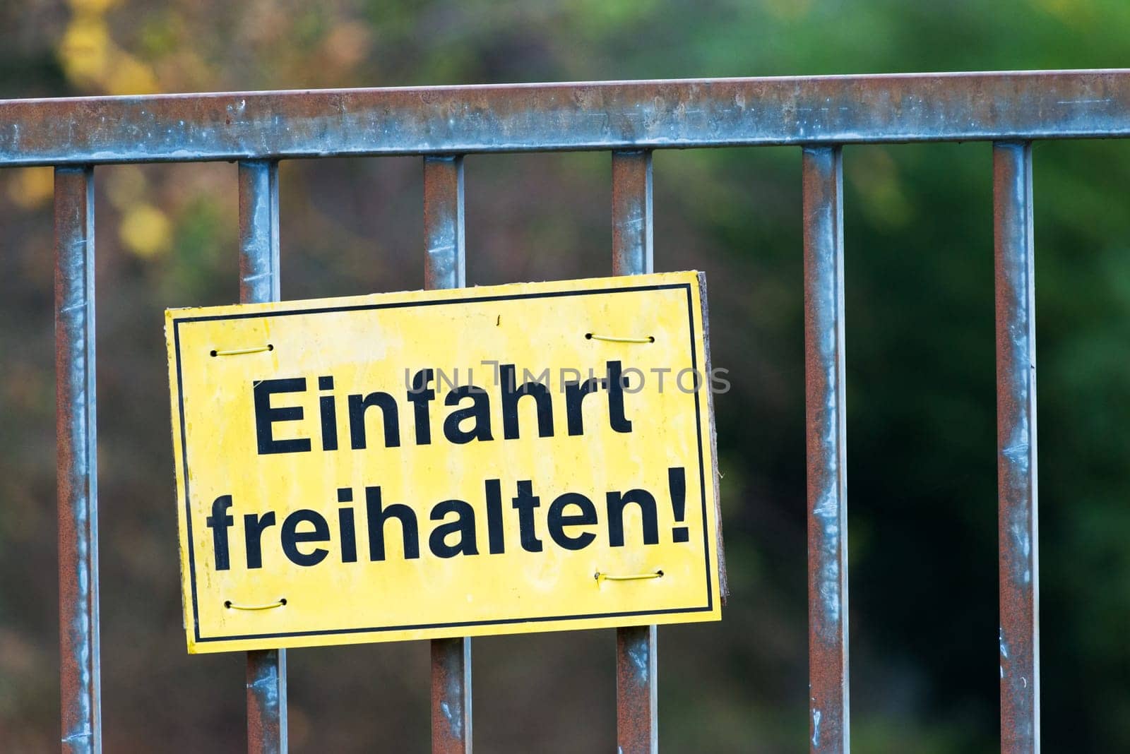 Einfahrt bitte freihalten. (keep entrance clear) Old historical iron gate. White sign with the inscription "keep entrance clear"". The Background is blurred"