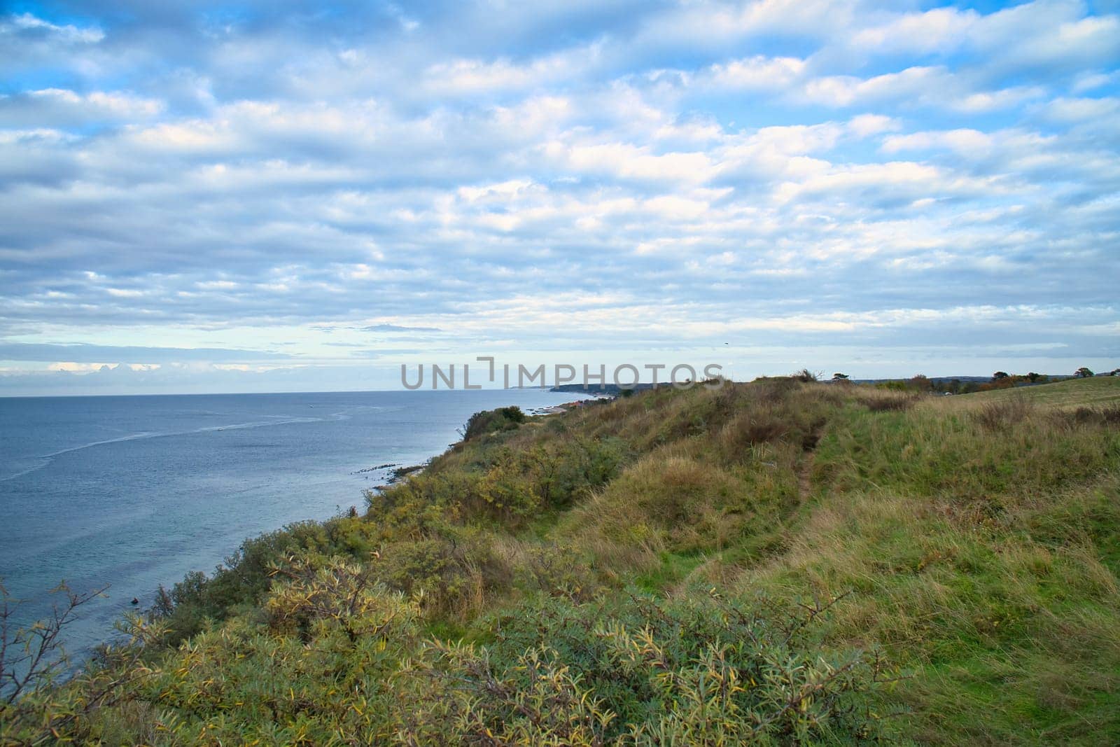Hundested, Denmark on the cliff overlooking the sea. Baltic Sea coast, grassy meadow, beach. Clouds on horizon. Landscape photo from Scandinavia.