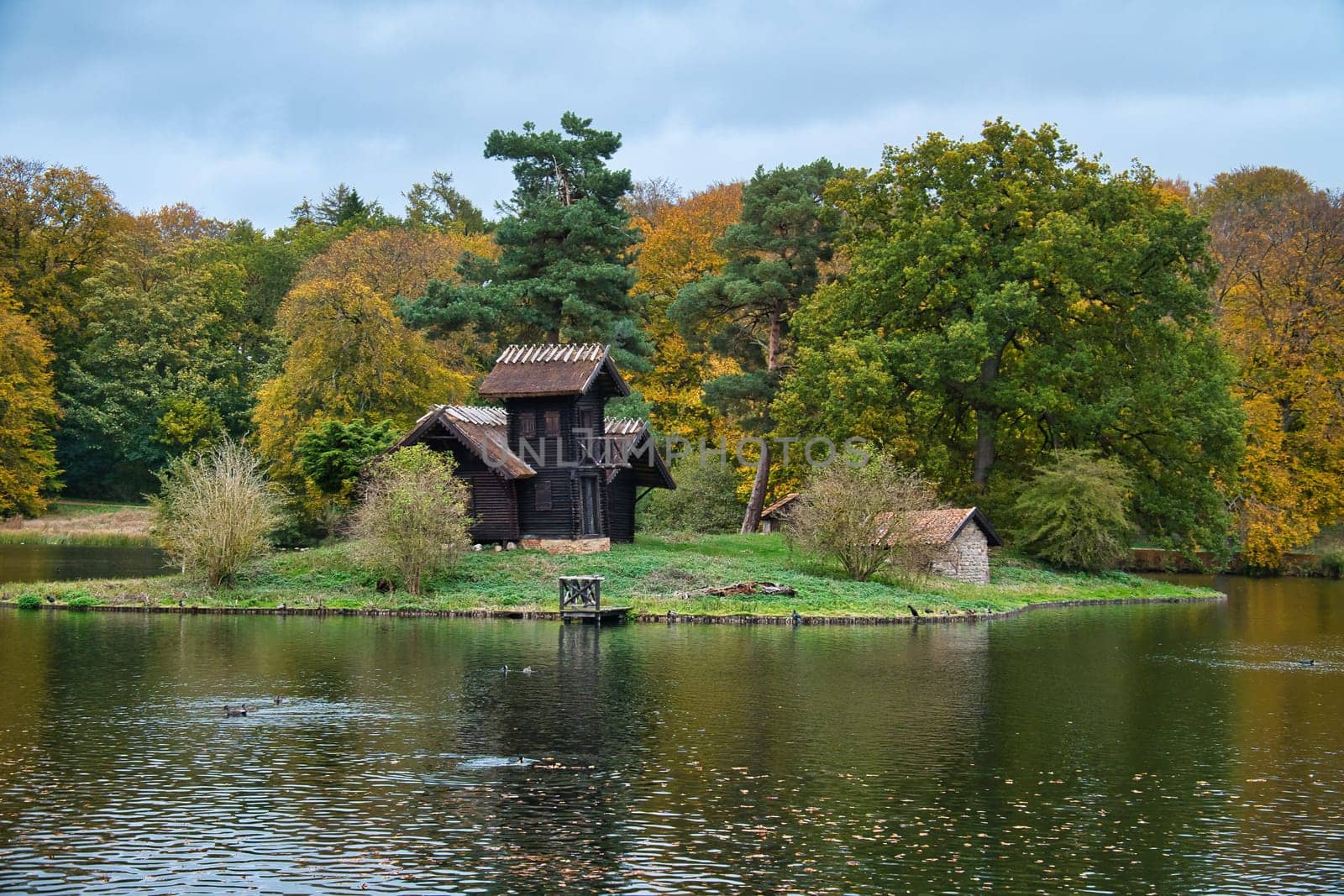 Frederiksborg castle park lake with island on which the wood Louises stands. Walk in Denmark
