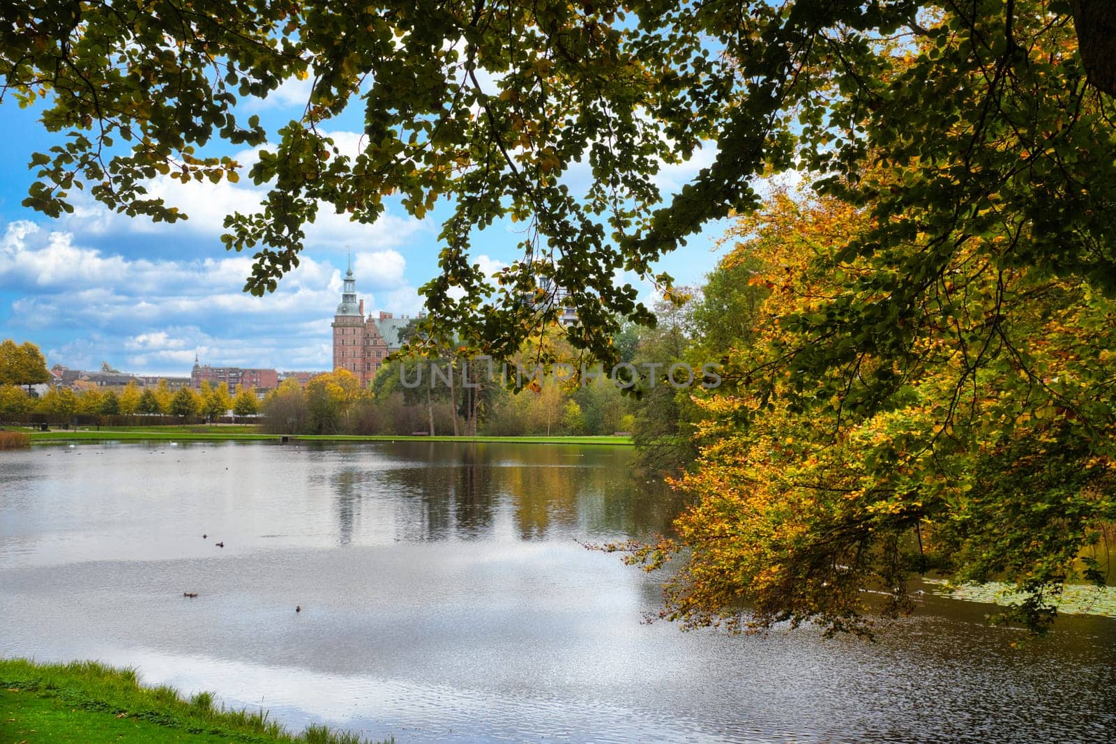 Frederiksborg castle park with created lake, in the background the castle. Bright colors of the leaves. Walk in Denmark