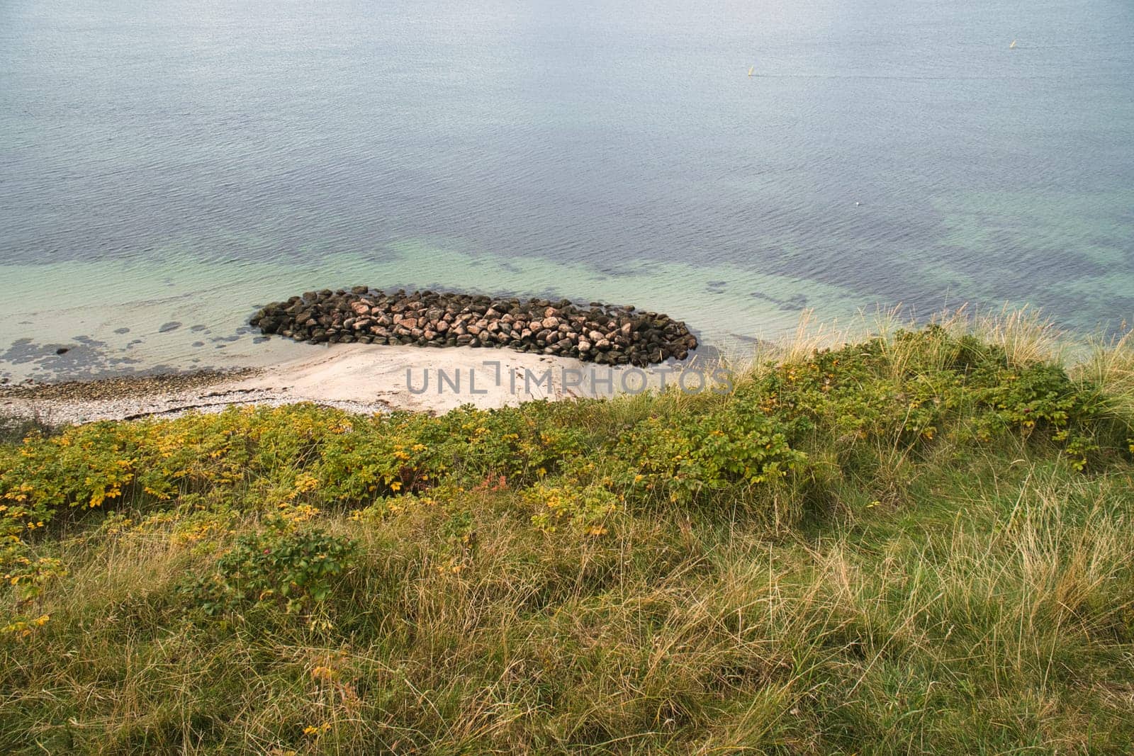 Hundested, Denmark on the cliff overlooking the sea. Baltic Sea coast, grassy meadow, beach. Clouds on horizon. Landscape photo from Scandinavia.