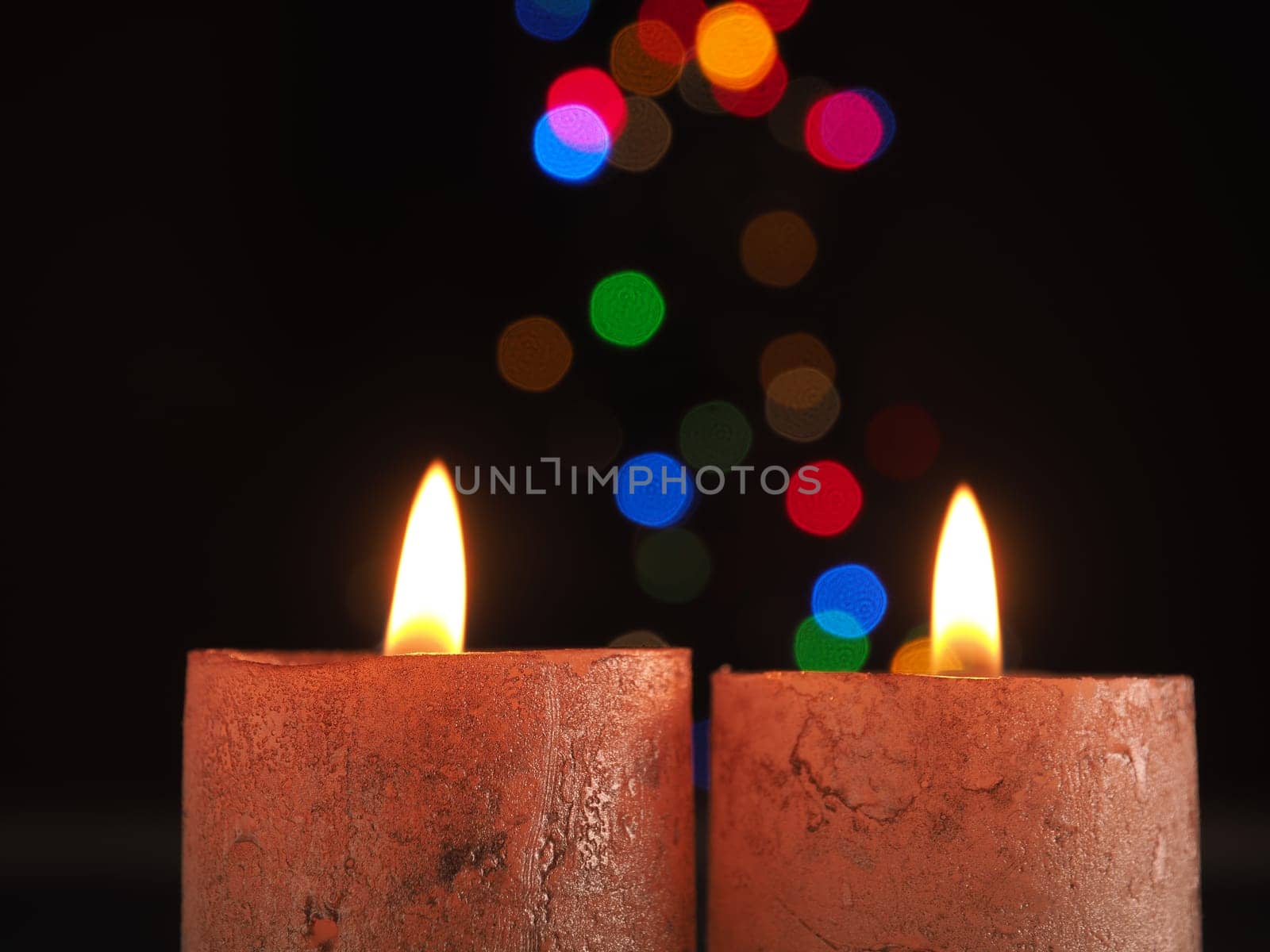 Two Advent candles burning with Christmas lights bokeh and space for text