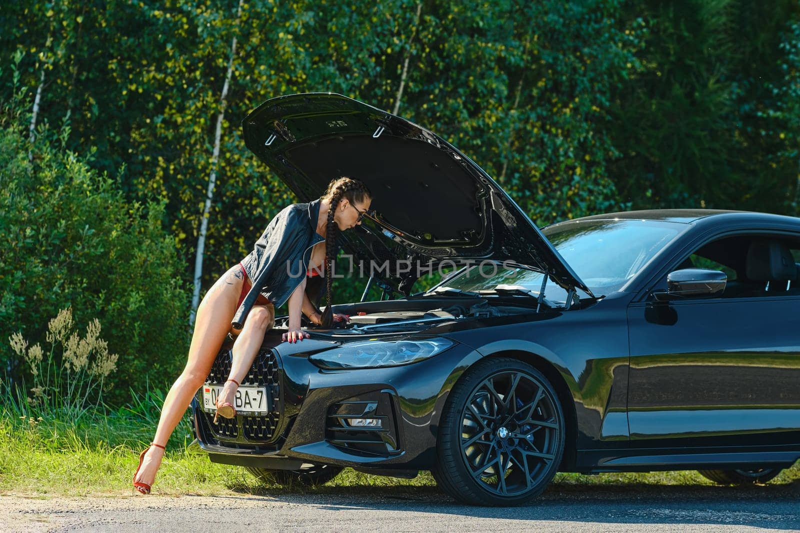 September 12, 2021, Minsk, Belarus - driver woman looks into the engine of her broken-down car