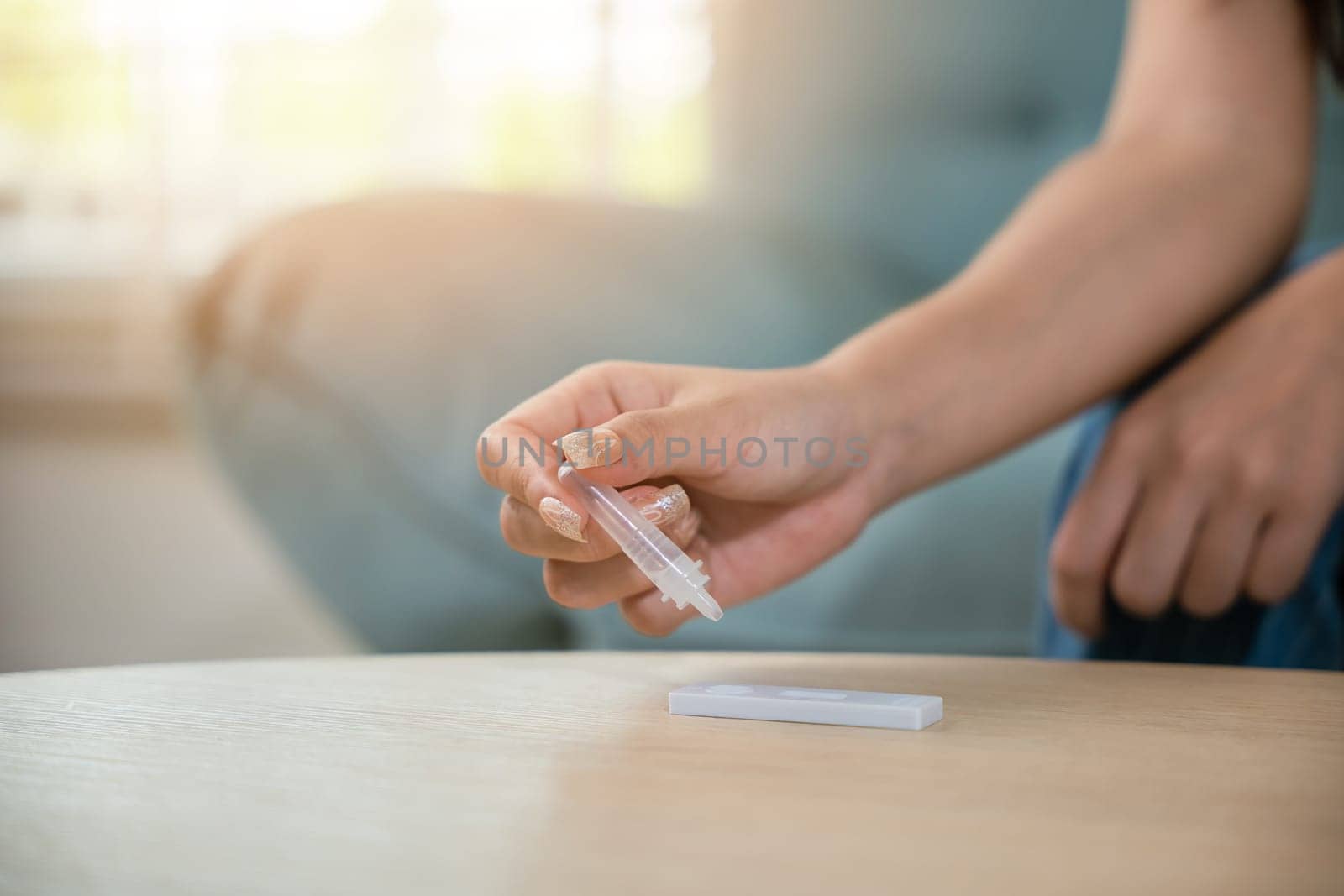 Close up woman hands using rapid antigen test kit for selftest, female four drops of liquid to perform fast coronavirus ATK self test at home in living room on sofa after lockdown and Home Isolation