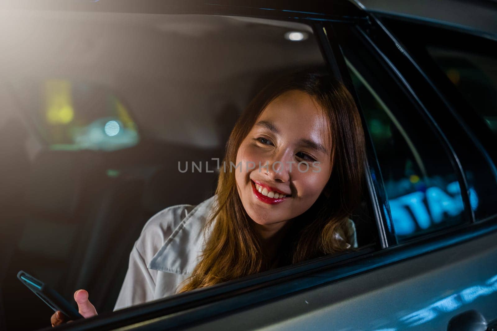 Asian businesswoman commuting from office in Taxi backseat with mobile phone on road in city at night after late work, Beautiful woman using smartphone sitting back seat her car in urban