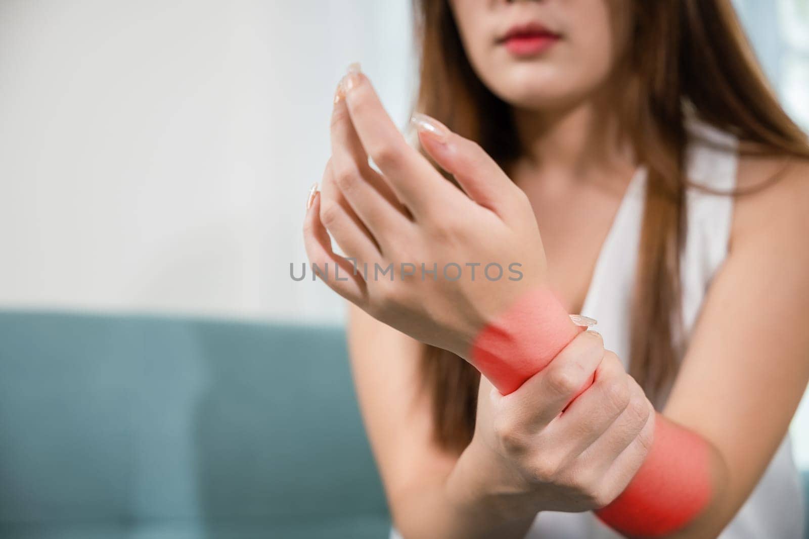 Closeup hand. Asian woman hand problem injury feeling joint pain, young female sitting on sofa holds suffering her wrist at home, performing self-massage, Health care and medical concept