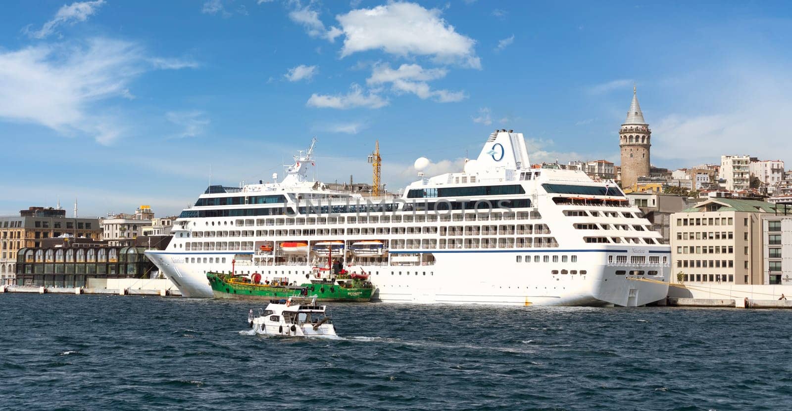 Nautica Majuro, Huge cruise ship docked at terminal of Galataport, a mixed use development located along the Bosphorus, in Karakoy neighbourhood, with Galata tower in the far end, Istanbul, Turkey