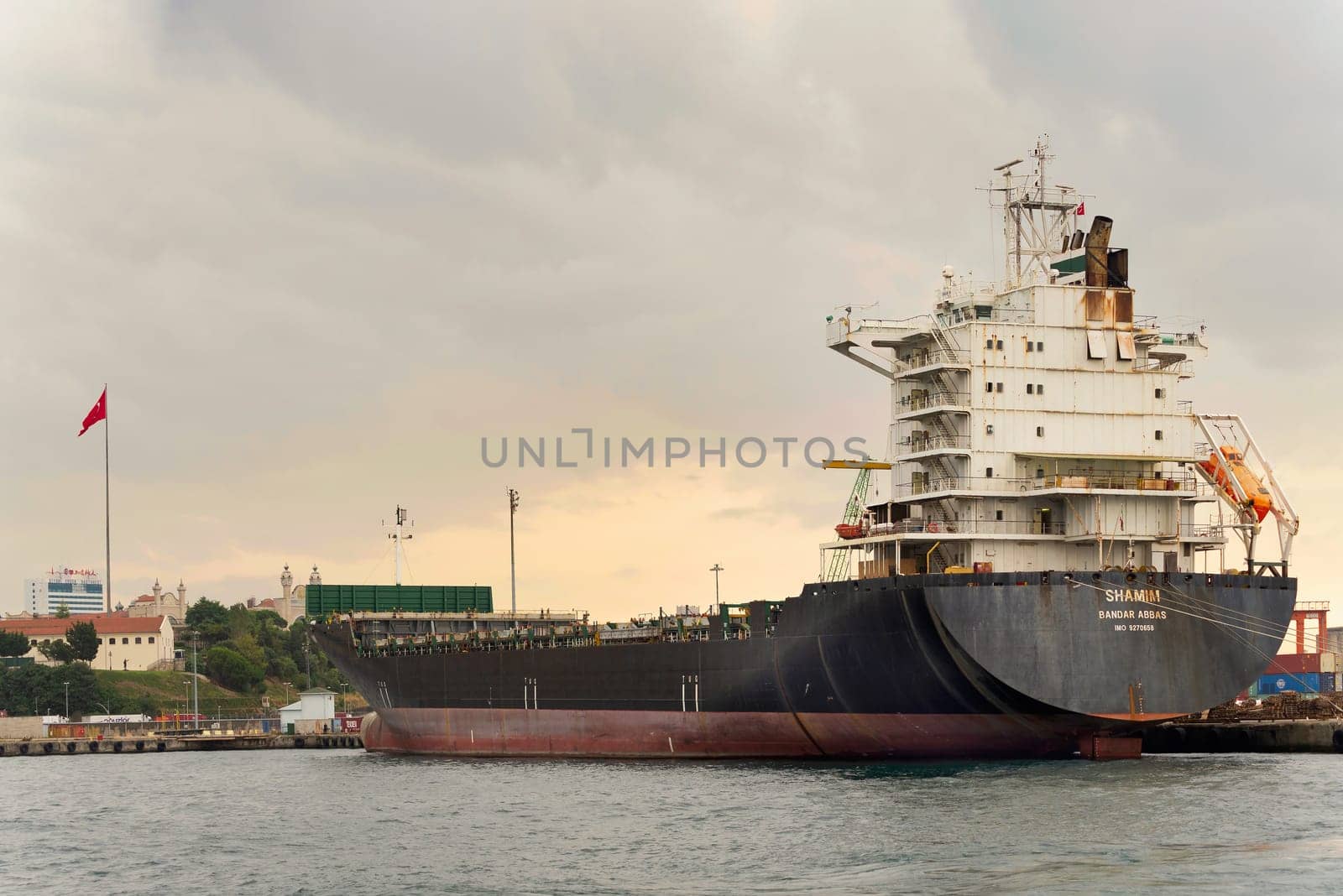 Bandar Abbas, container ship, docked at the shipyard of the Port of Haydarpasha with Turkish flag in the background, at Kadikoy district, Istanbul, Turkey