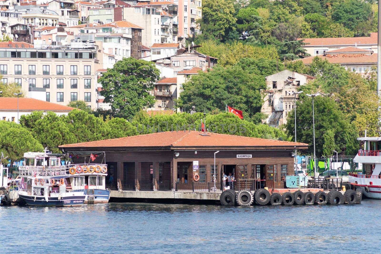 Istanbul, Turkey - September 1, 2022: Golden Horn, Kasim Pasa Ferry Terminal with houses and dense green trees in the background