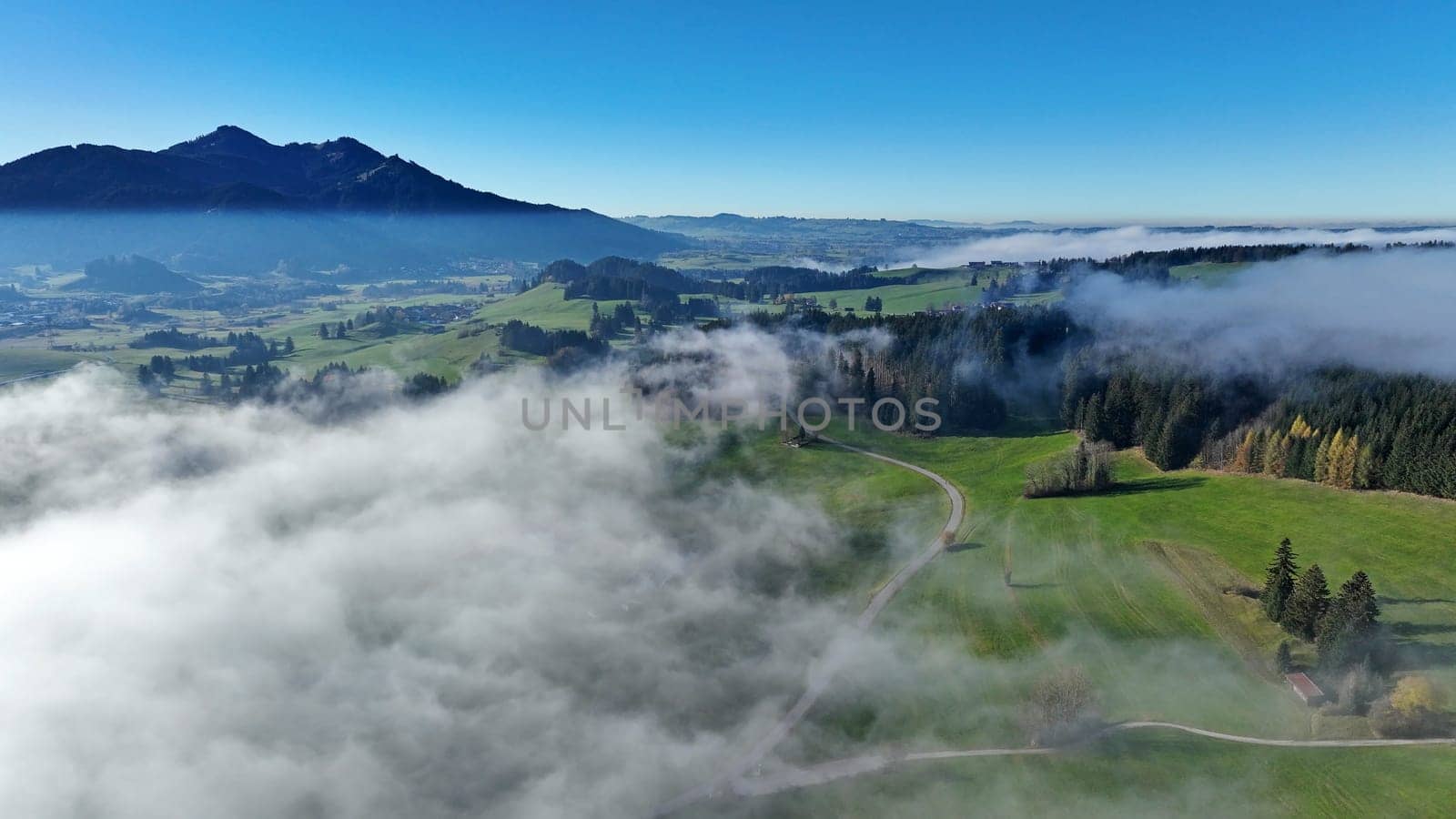 Aerial drone shot of Allgäu landscape with road in autumn with fog