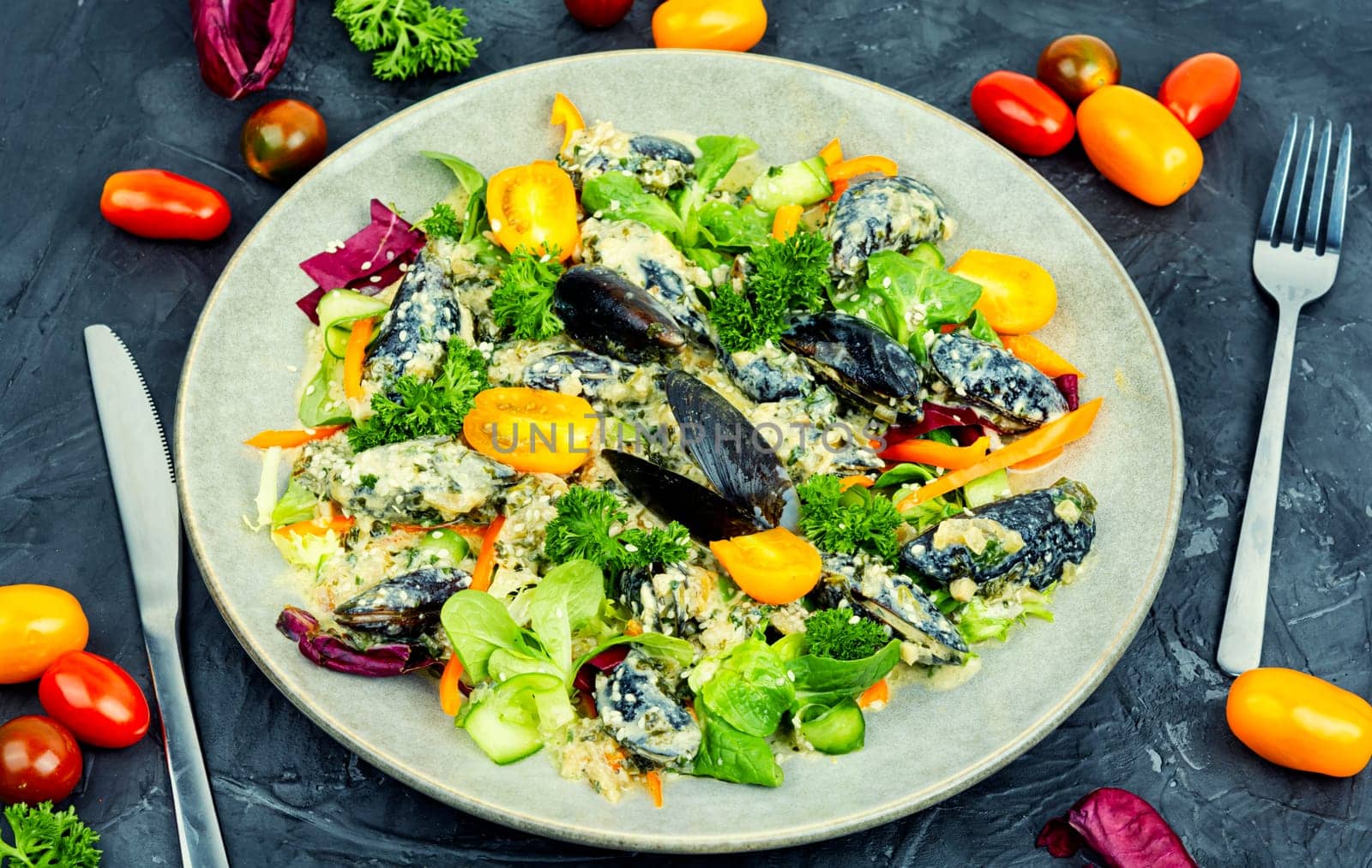 Plate with a salad of fresh vegetables, herbs and mussels.
