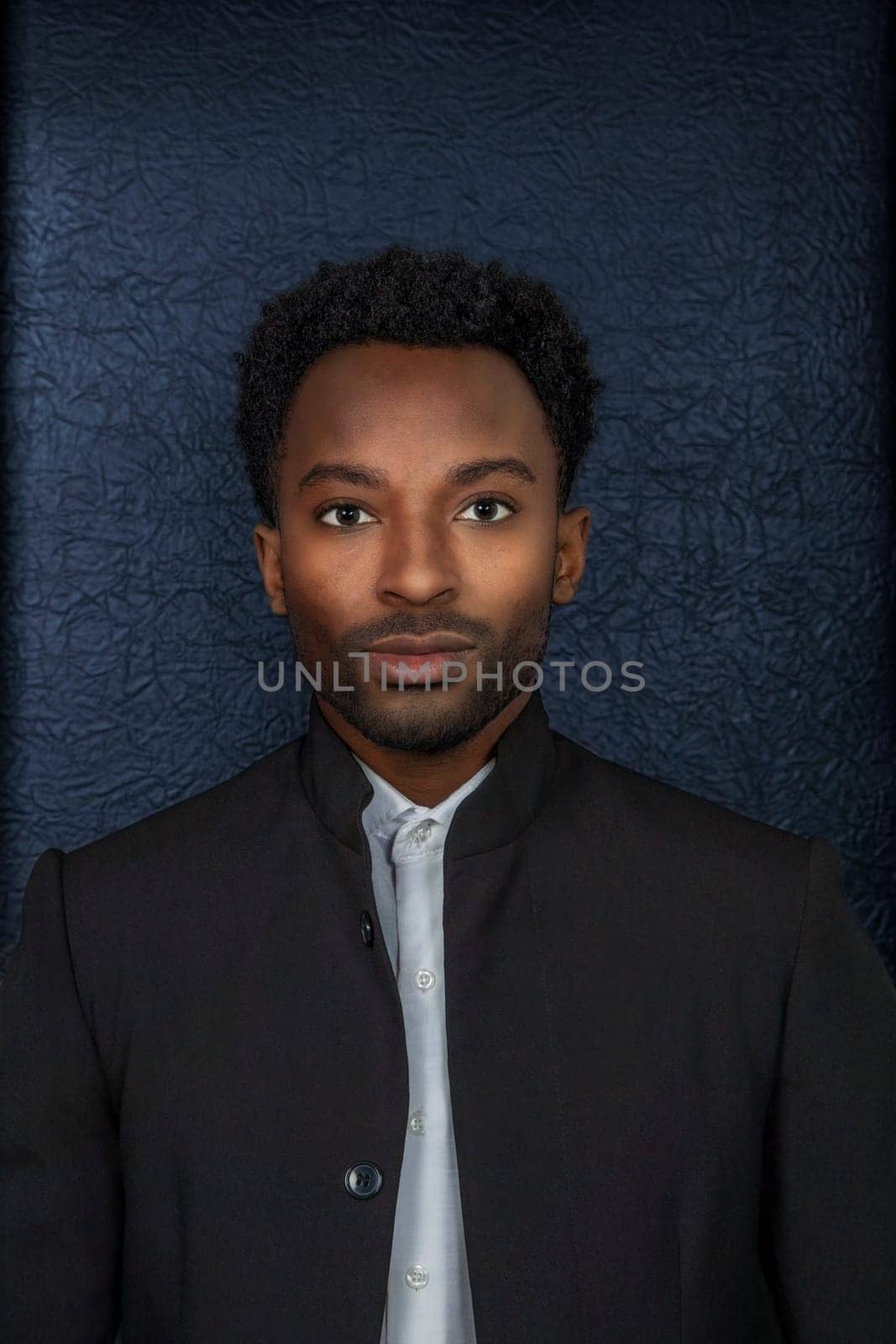 twenty year old man headshot suit style on black background vertical dark portrait serious businessman