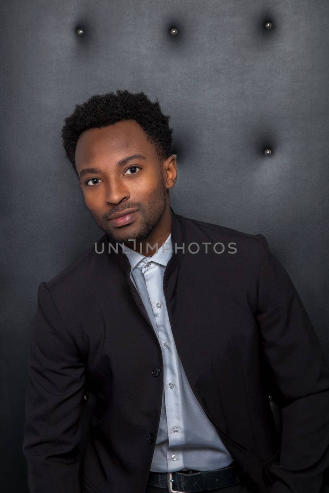 twenty year old conservative businessman suit style on black leather background vertical dark portrait of serious man lounge