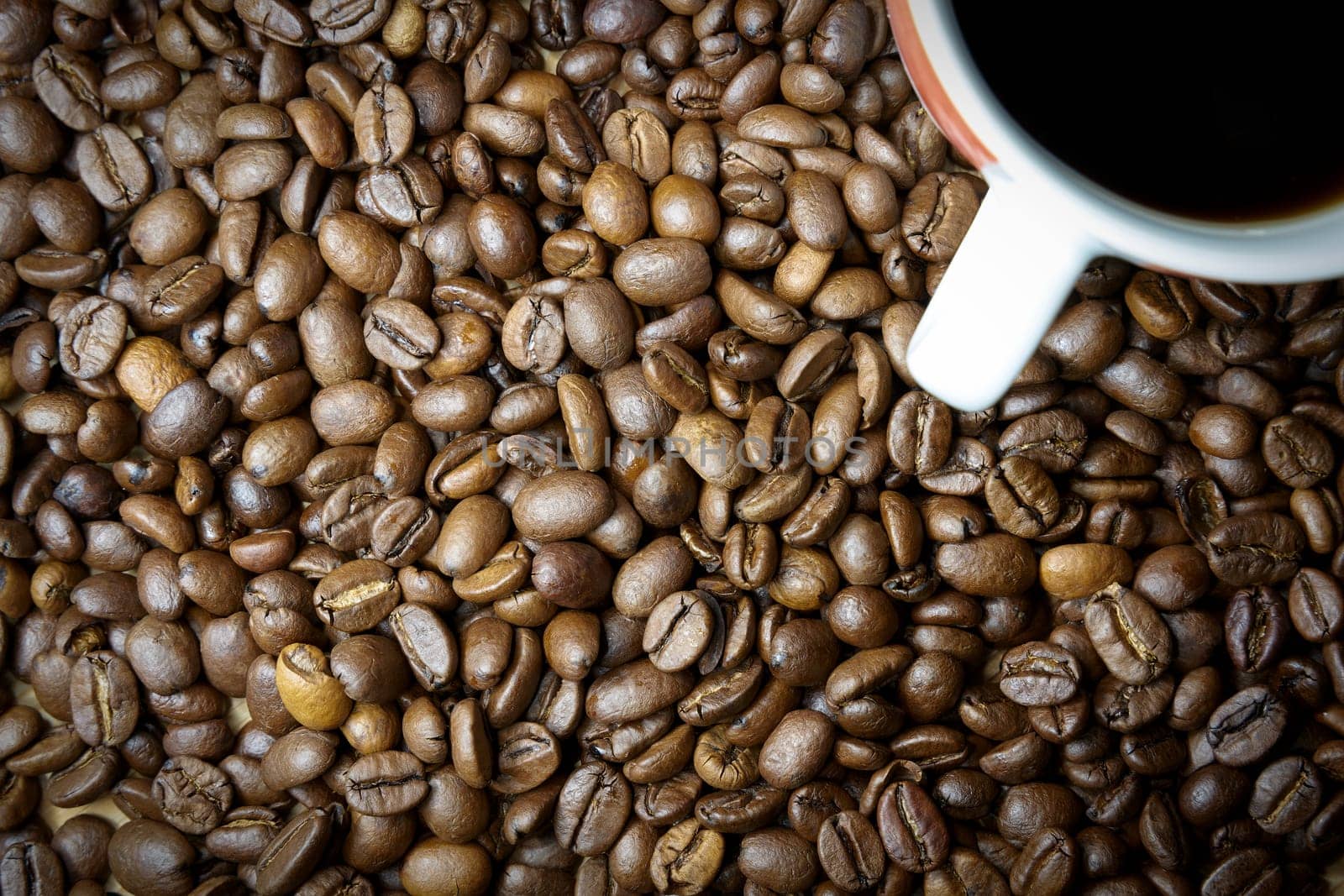 roasted coffee beans and a cup with coffee on a table