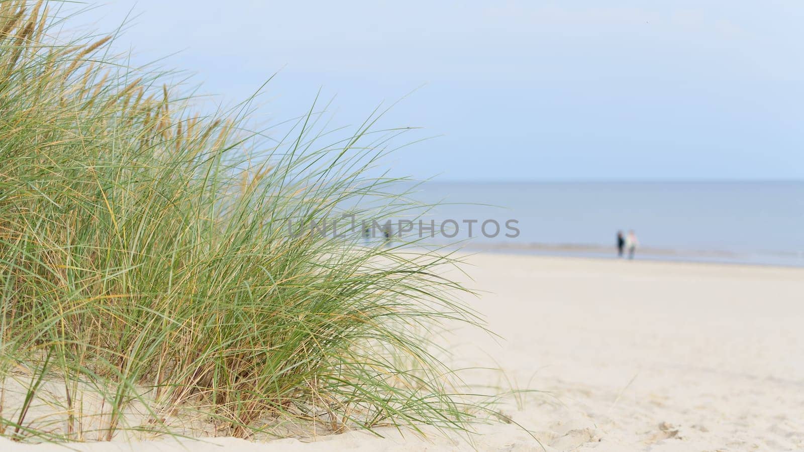 Beach on the coast of Swinoujscie on the Polish Baltic Sea coast. In the background blurry walkers.