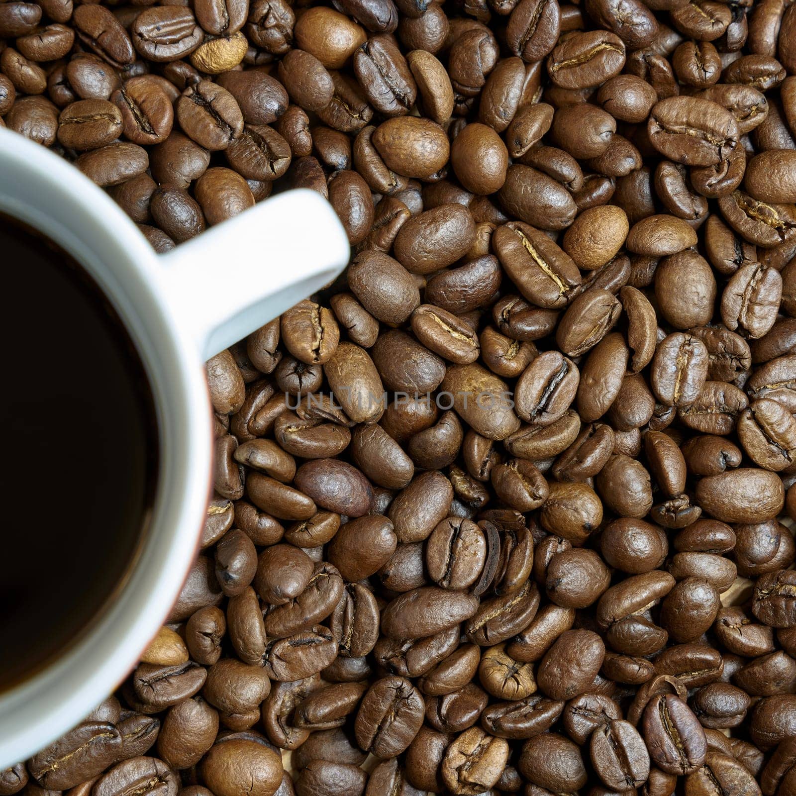 roasted coffee beans and a cup with coffee on a table