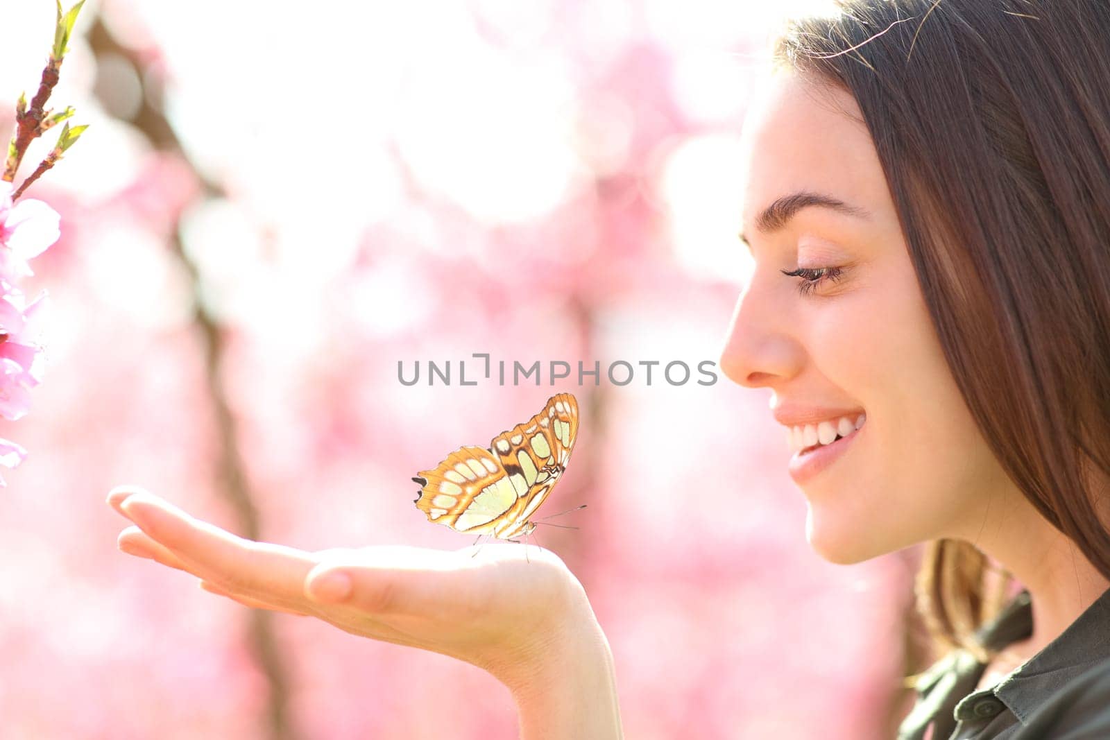 Happy woman with a butterfly in the hand looking it