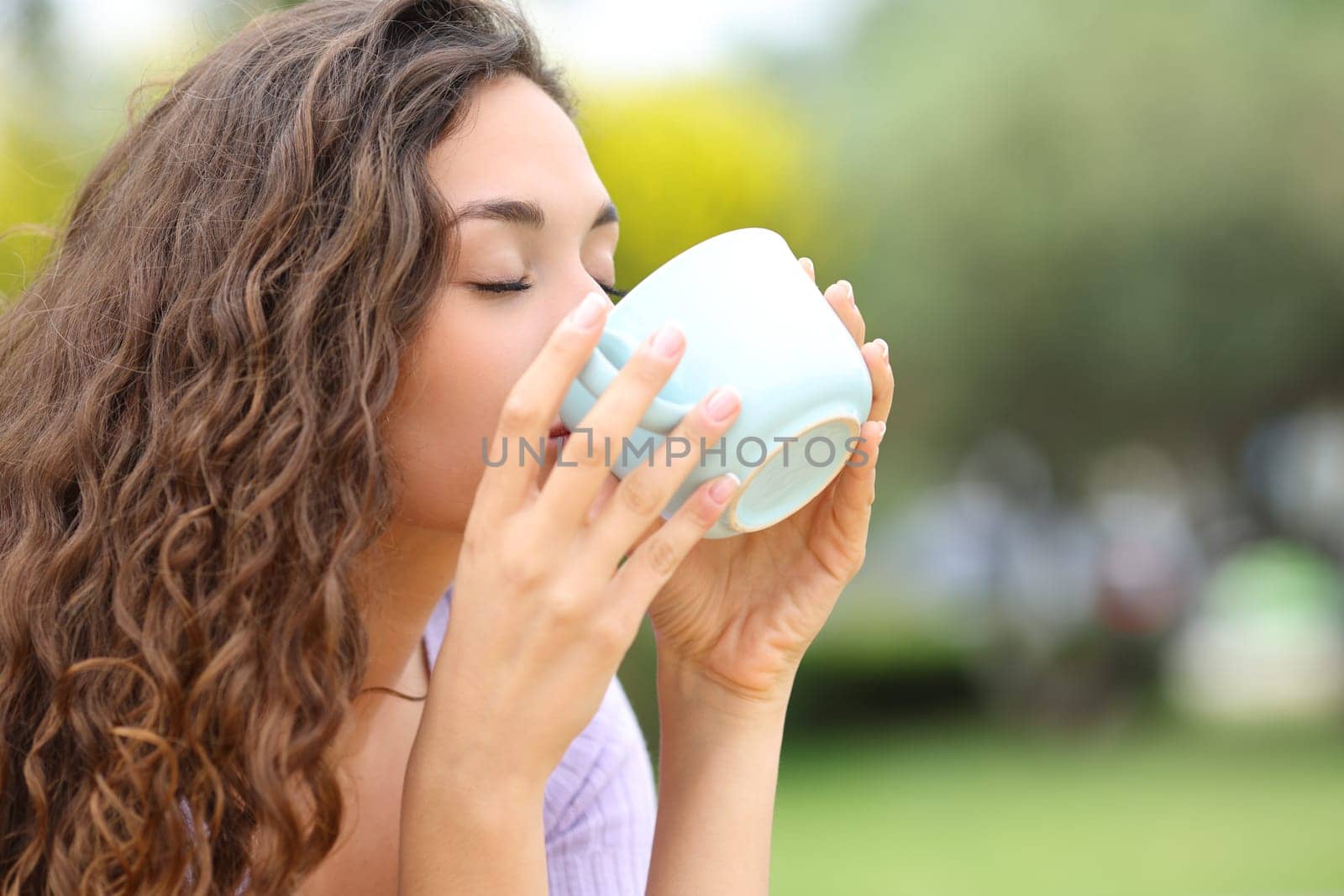 Woman drinking coffee from mug in a park