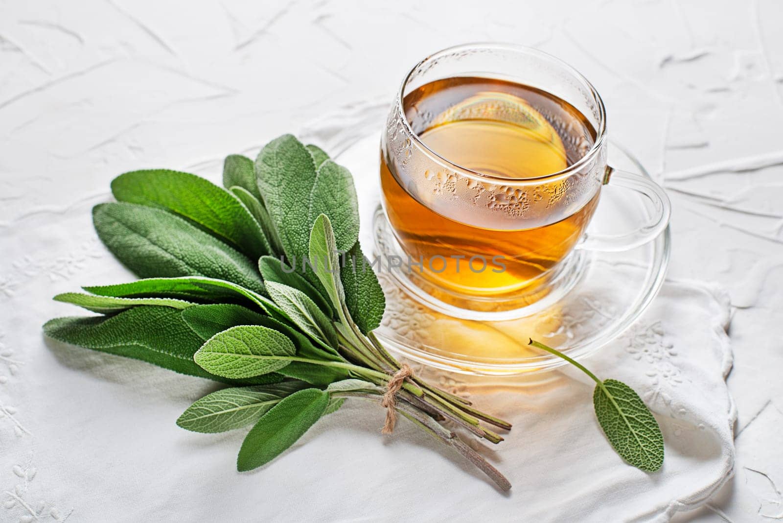 Sage tea cup and sage leaves on white table close up