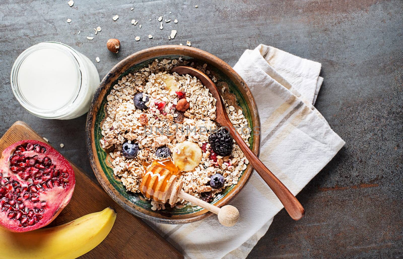 A bowl of muesli served with fresh fruit nuts and honey. Oatmeal plate. Healthy food, diet. Top view.