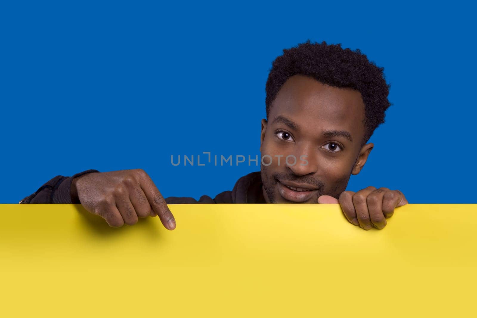 man holding and pointing board copy space background presentation banner poster yellow cardboard on blue background