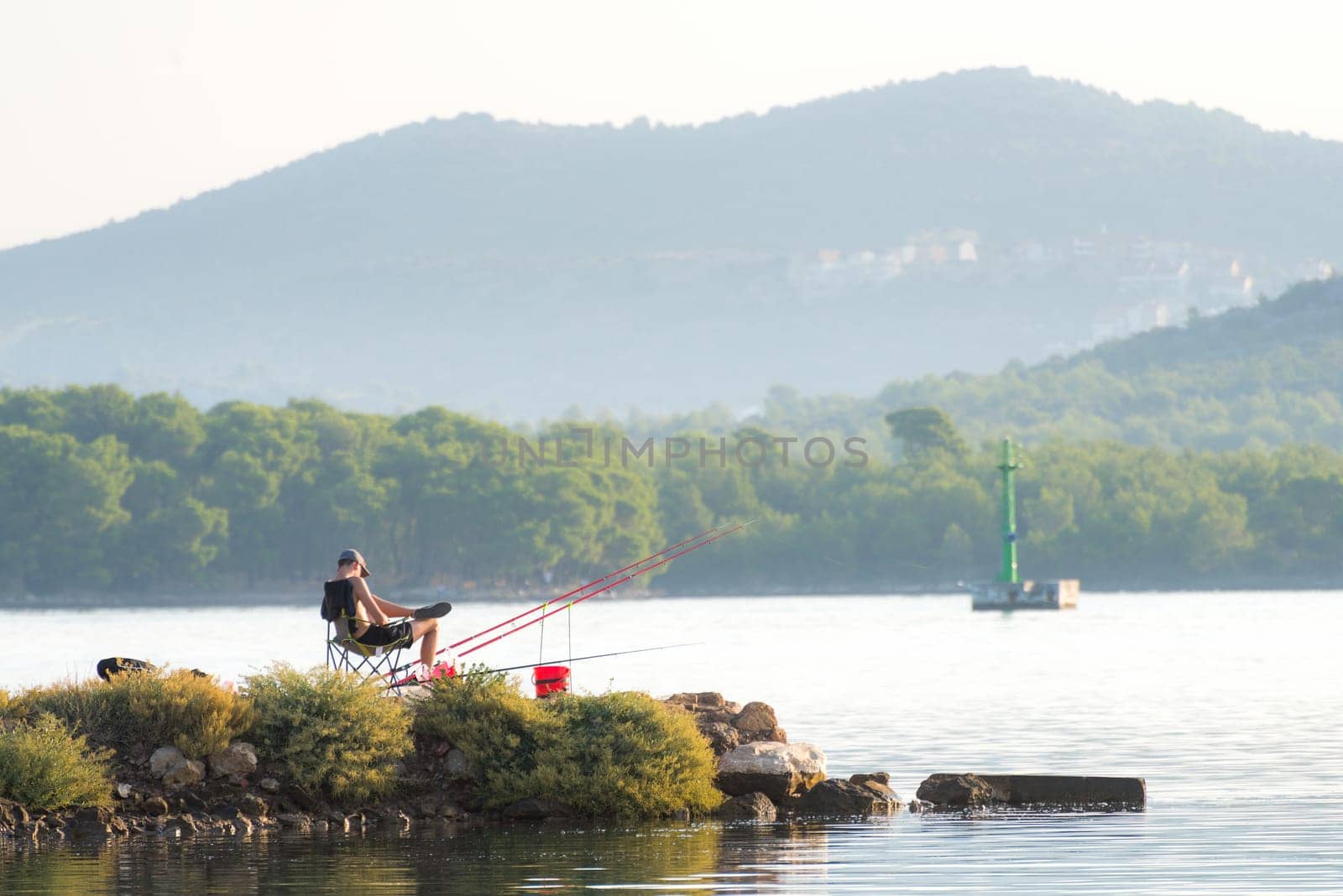 young man is sitting and fishing on canal of sveti ante in sibenik croatia