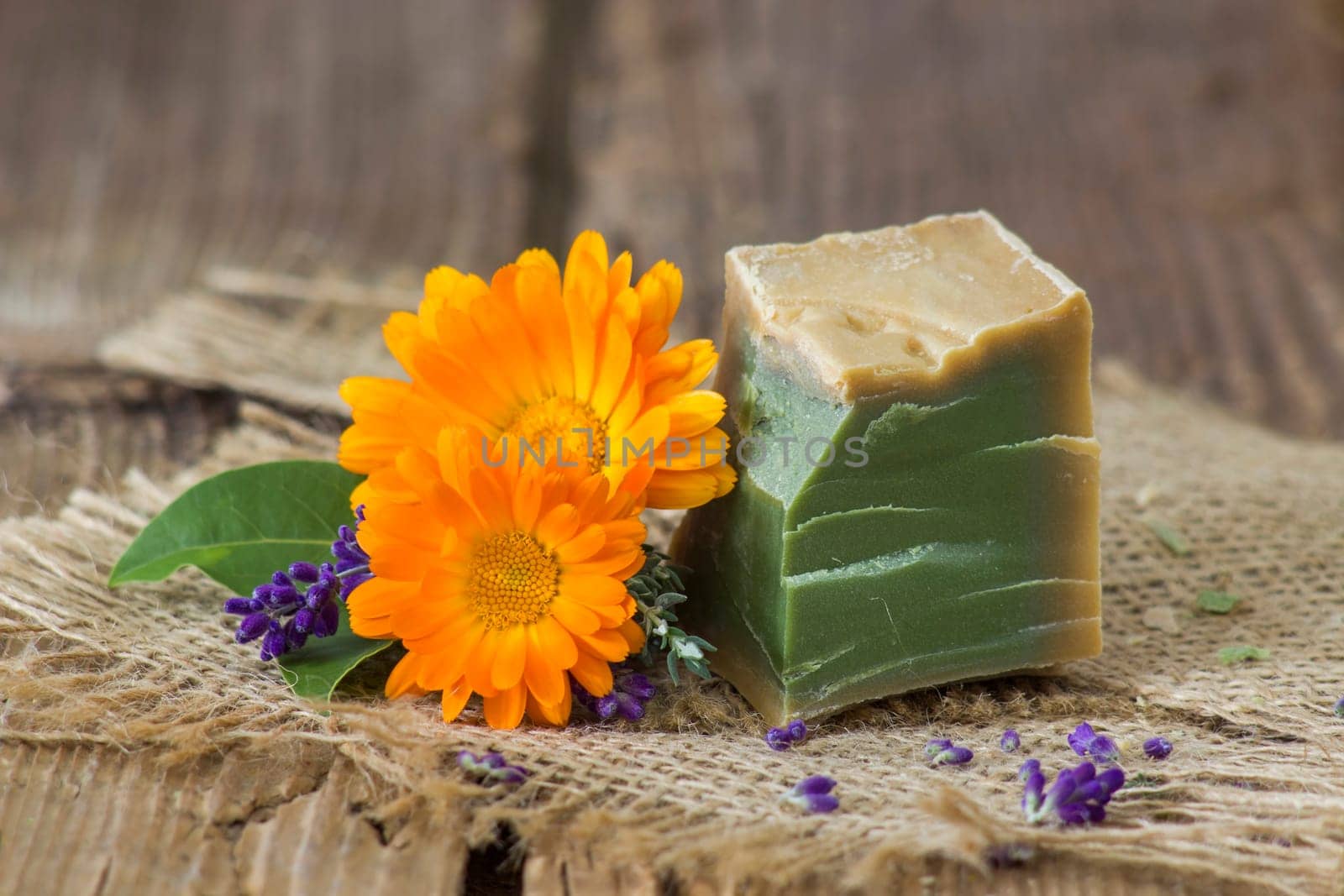 Natural handmade soap with calendula, lavender and herbs on rustic wooden background