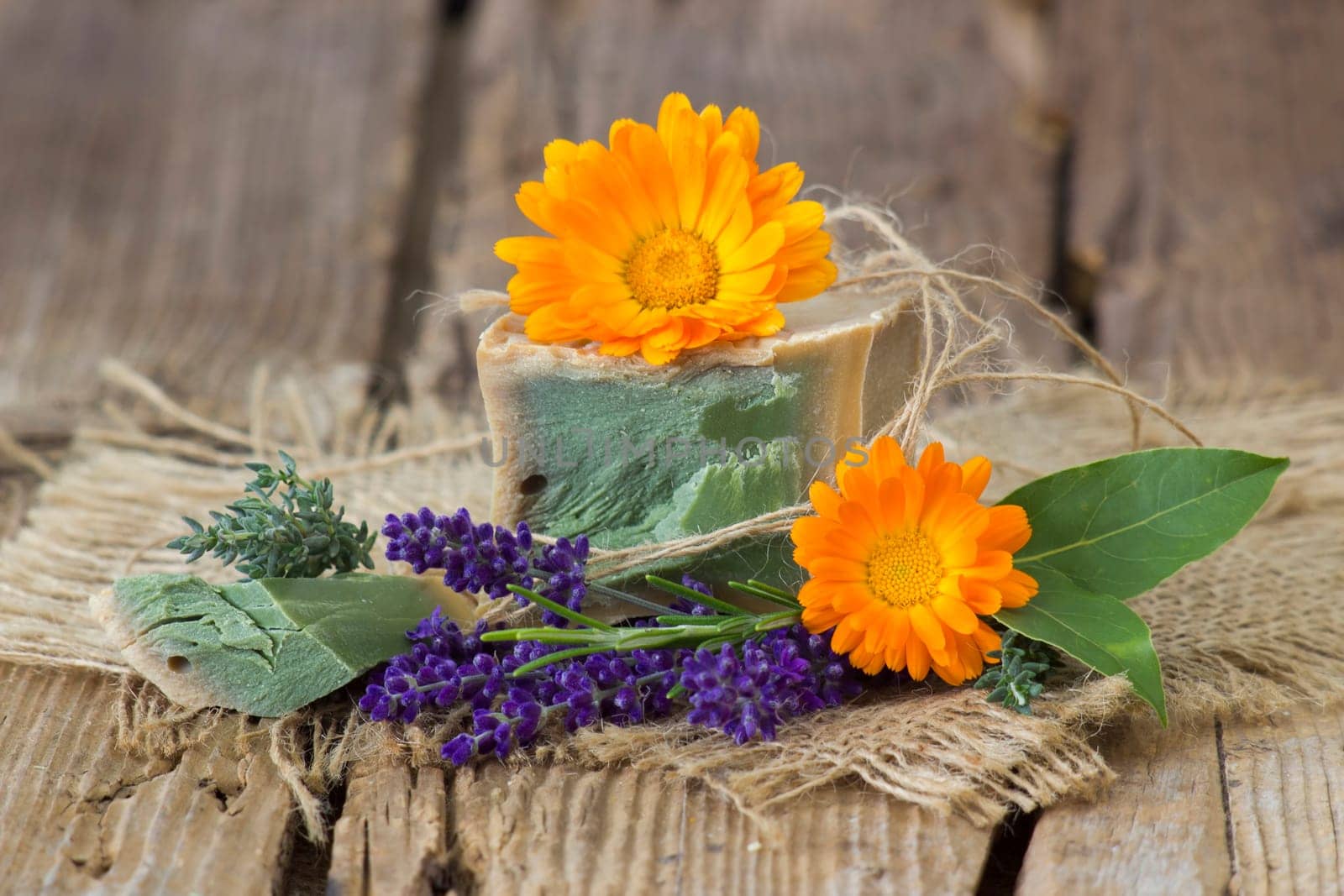Natural handmade soap with calendula, lavender and herbs on rustic wooden background