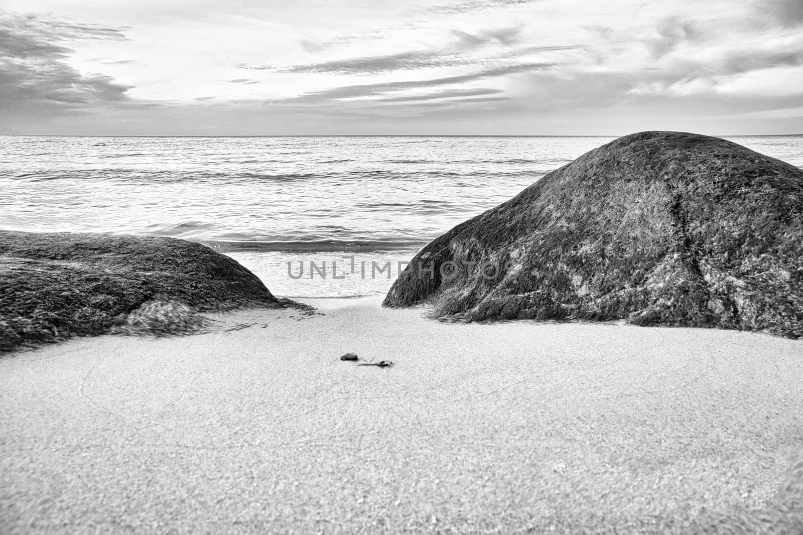 Big stone on the sandy beach in front of the sea with clouds in the sky. Denmark in Scandinavia. Landscape shot from nature in the north
