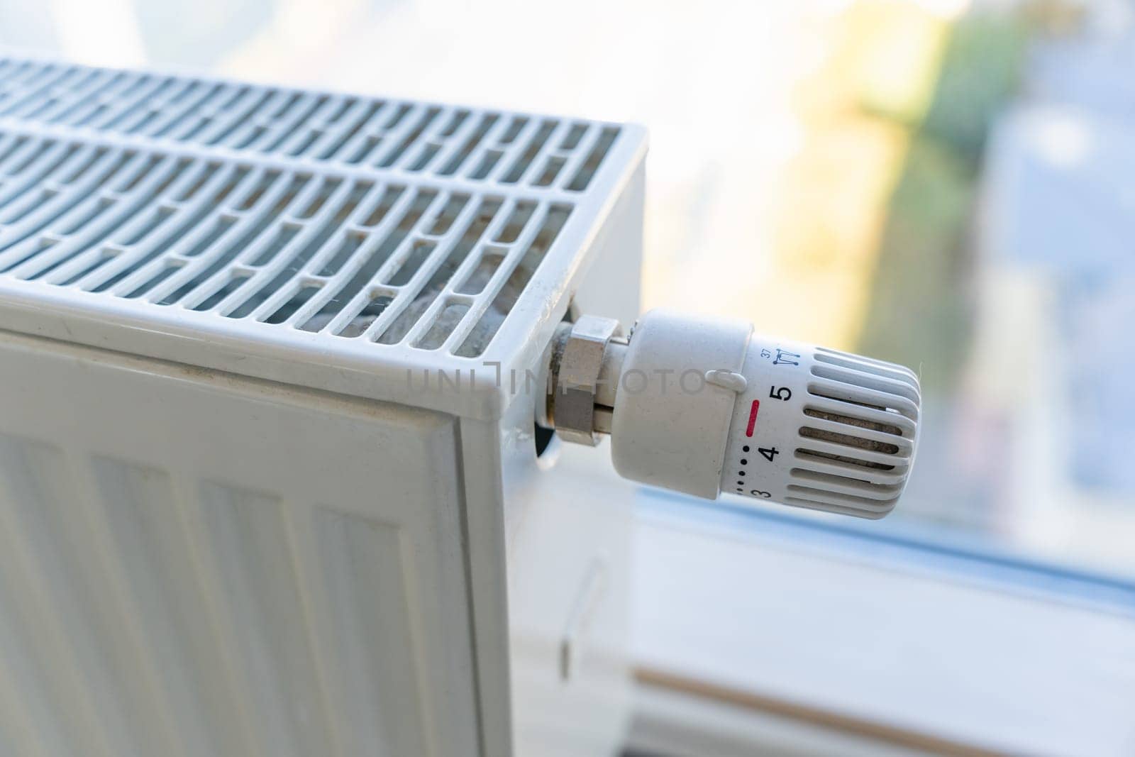 Heating radiator with adjustment knob set to the maximum value due to frost and low temperature. High prices for heat and utilities.