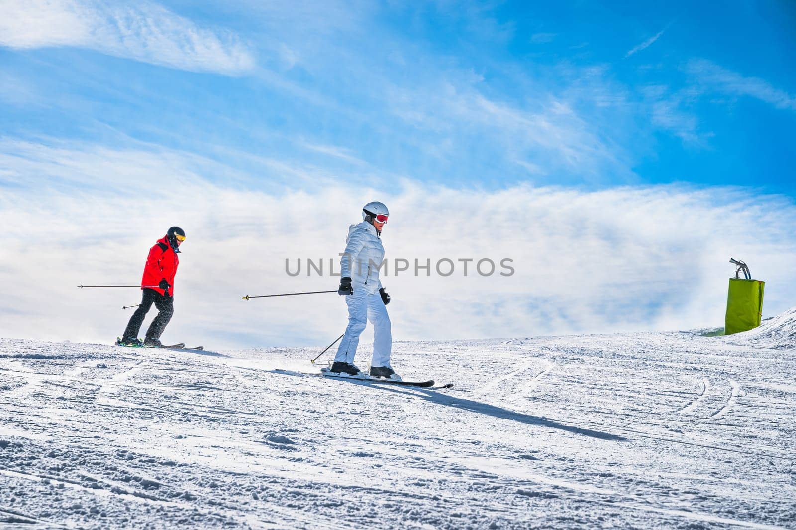 Couple, man and woman skiing down the ski slope or piste in Pyrenees Mountains. Winter ski holidays in El Tarter, Grandvalira, Andorra