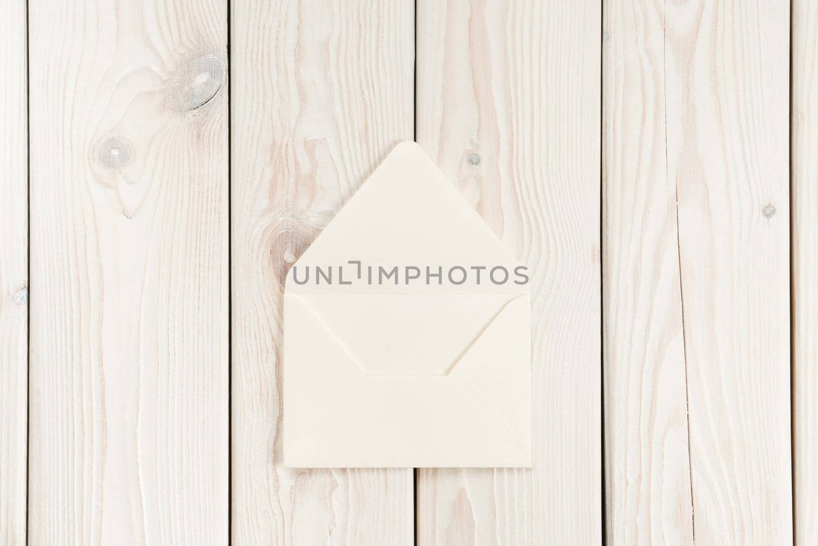 White craft handmade opened paper envelope laying on white wooden plank background. Post card message, letter sending. New delivery and traditional invitation. Copy space, mockup, clipping path
