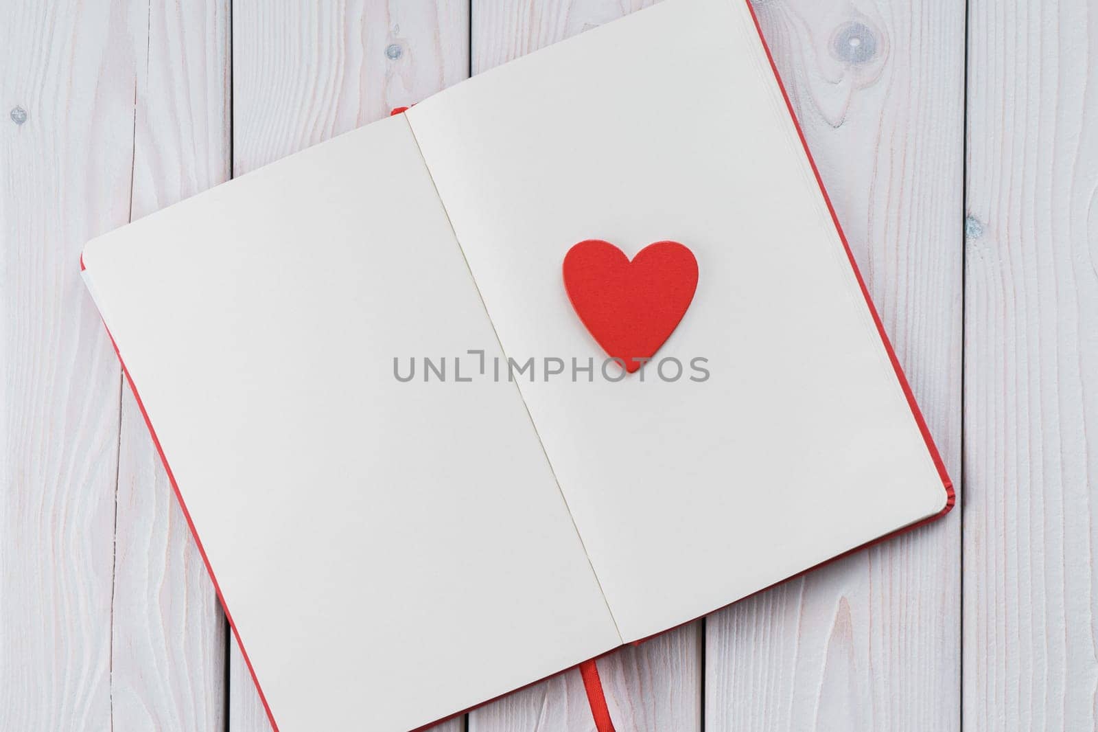 Red diary notebook with white papers, craft red paper heart on page. Love letter message for beloved people, confession and feelings for saint Valentine's Day or woman day. Copy space, top view