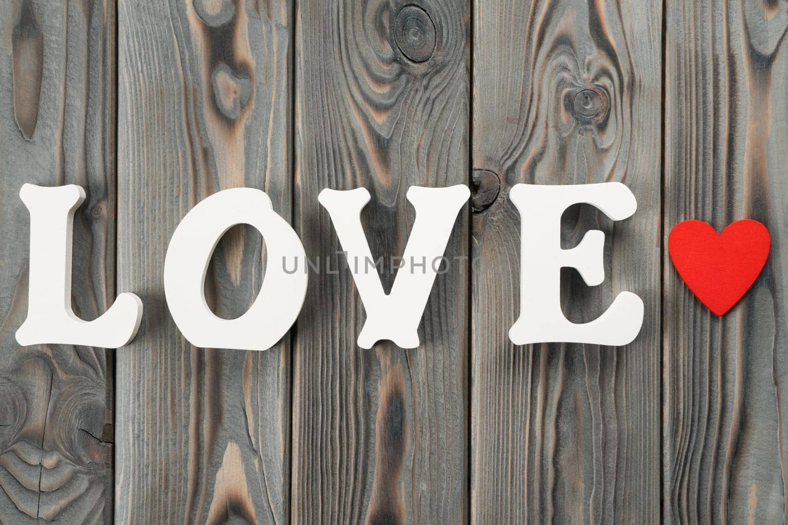 Close up of white plastic or wooden letters forming word love, red paper heart near the word. Love and care fore st Valentines day, 8 march, birthday or mother day. Top view, flat lay, copy space